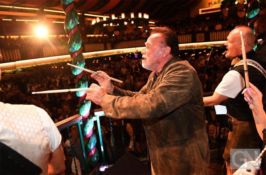 Ein Mann im Trachtenanzug spielt mit anderen Musikern auf einer Bühne vor großem Publikum.
