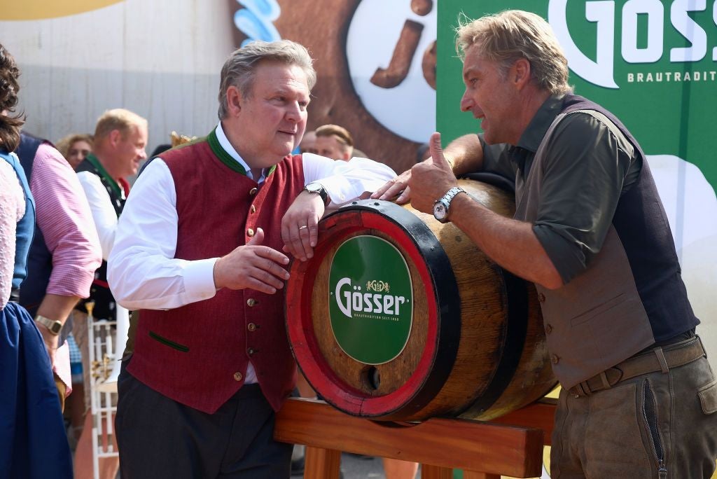 Zwei Männer unterhalten sich an einem Bierfass bei einem Volksfest in Wien.
