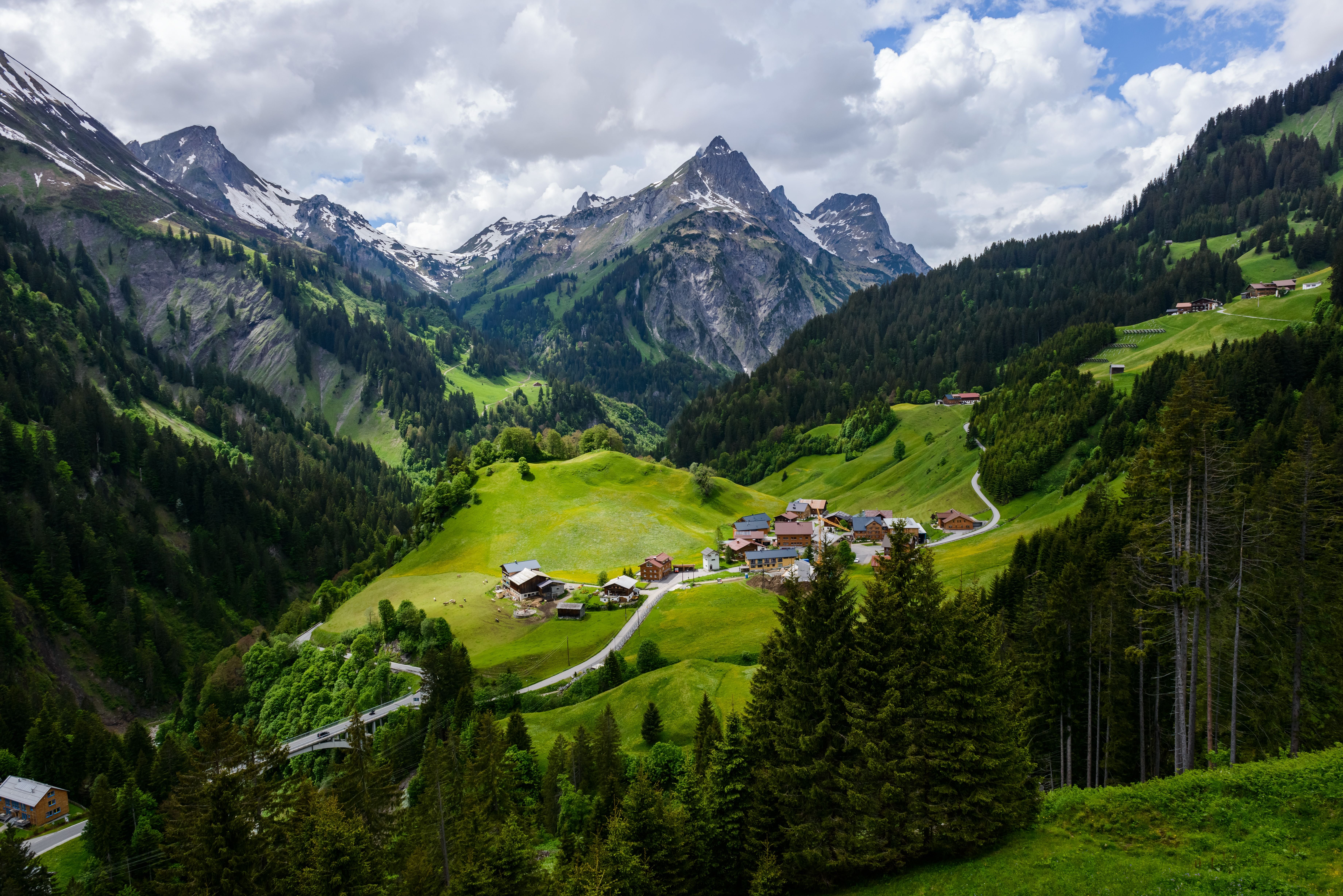 Bergdorf in den Alpen bei Schröcken, Österreich, mit grünen Wäldern und schneebedeckten Gipfeln.