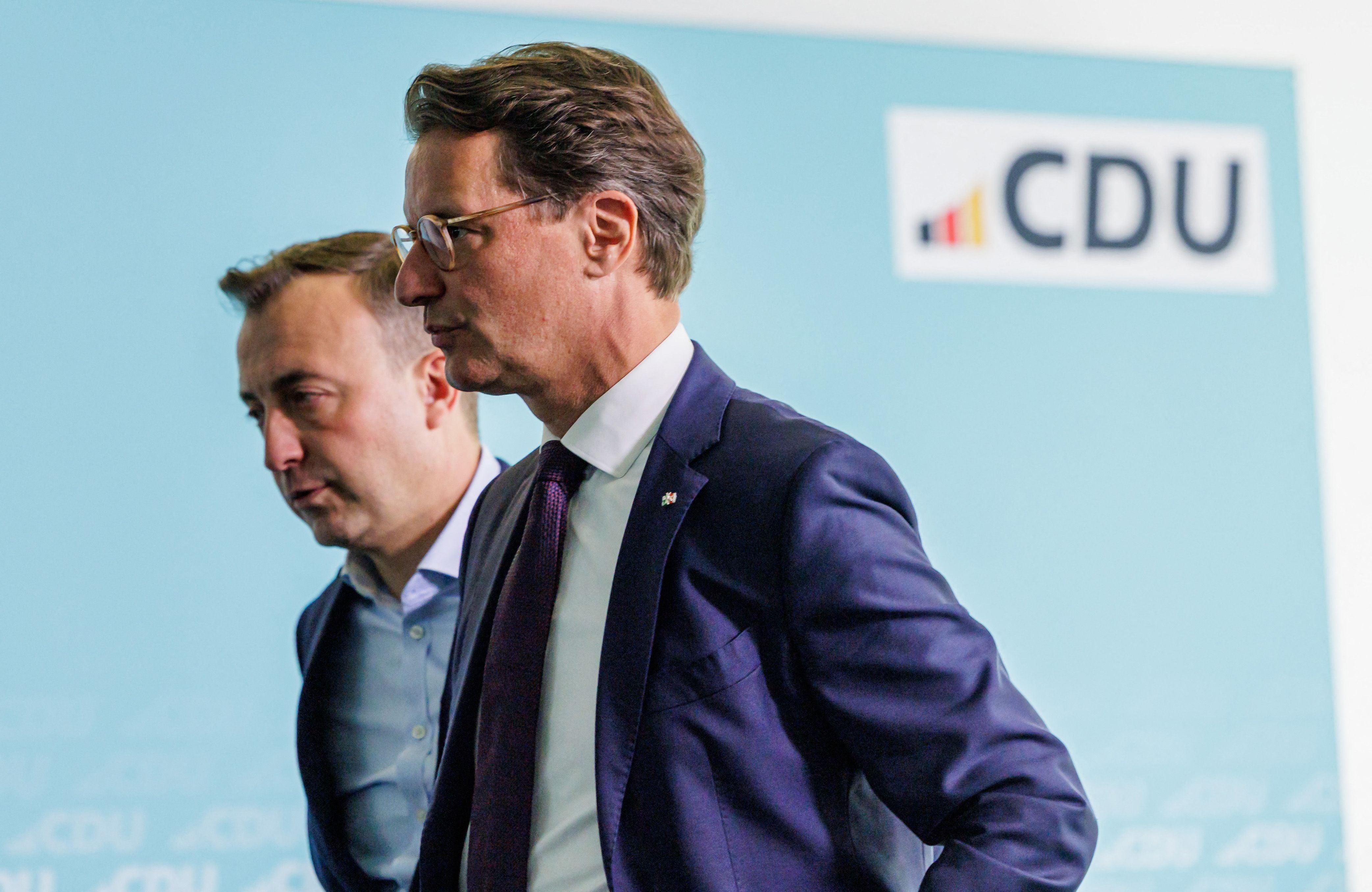 Zwei Männer im Anzug stehen vor einer CDU-Wand auf einer Pressekonferenz.