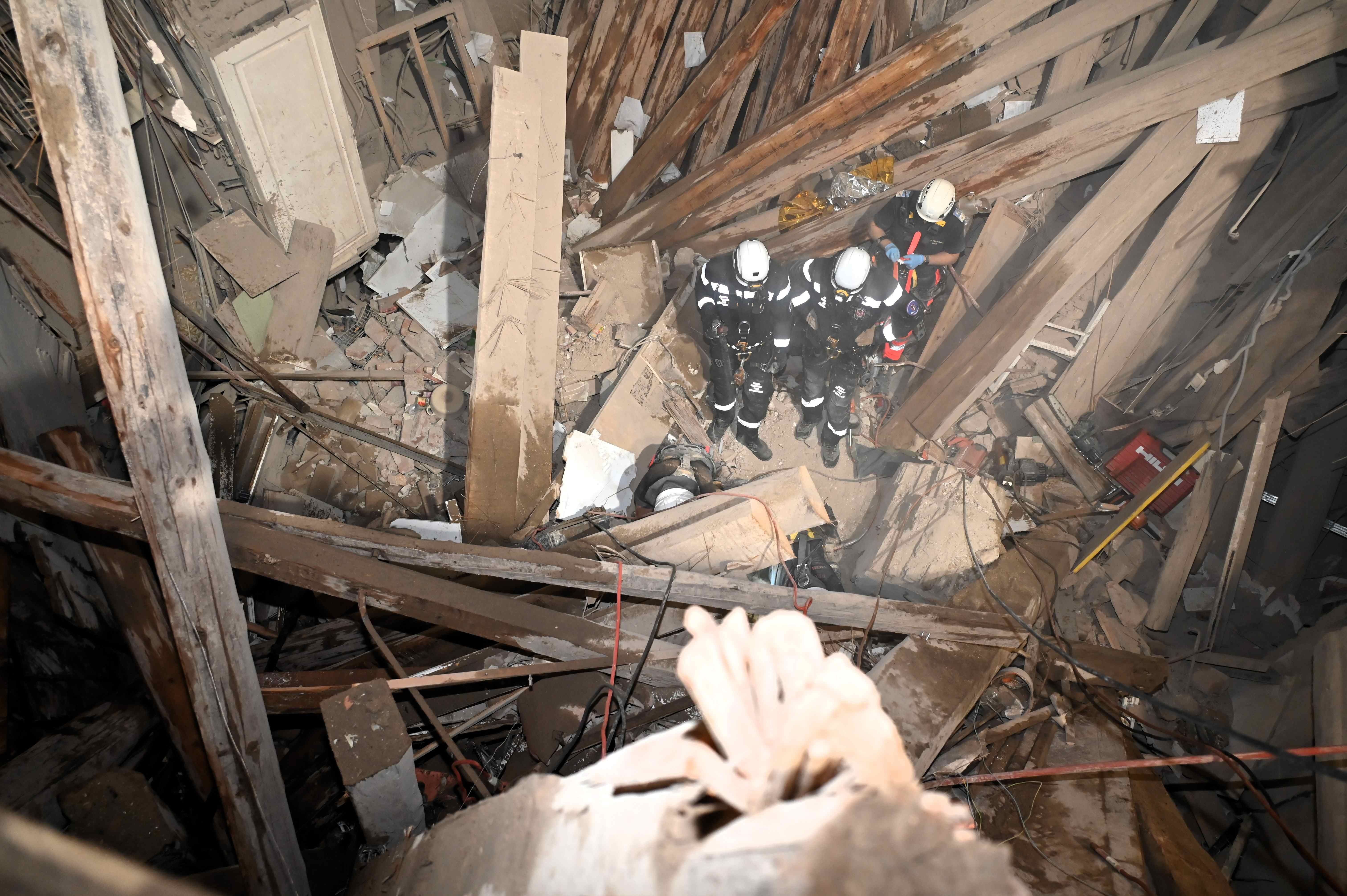 Einsatzkräfte stehen inmitten von Trümmern nach einem Teileinsturz eines Hauses in Wien.
