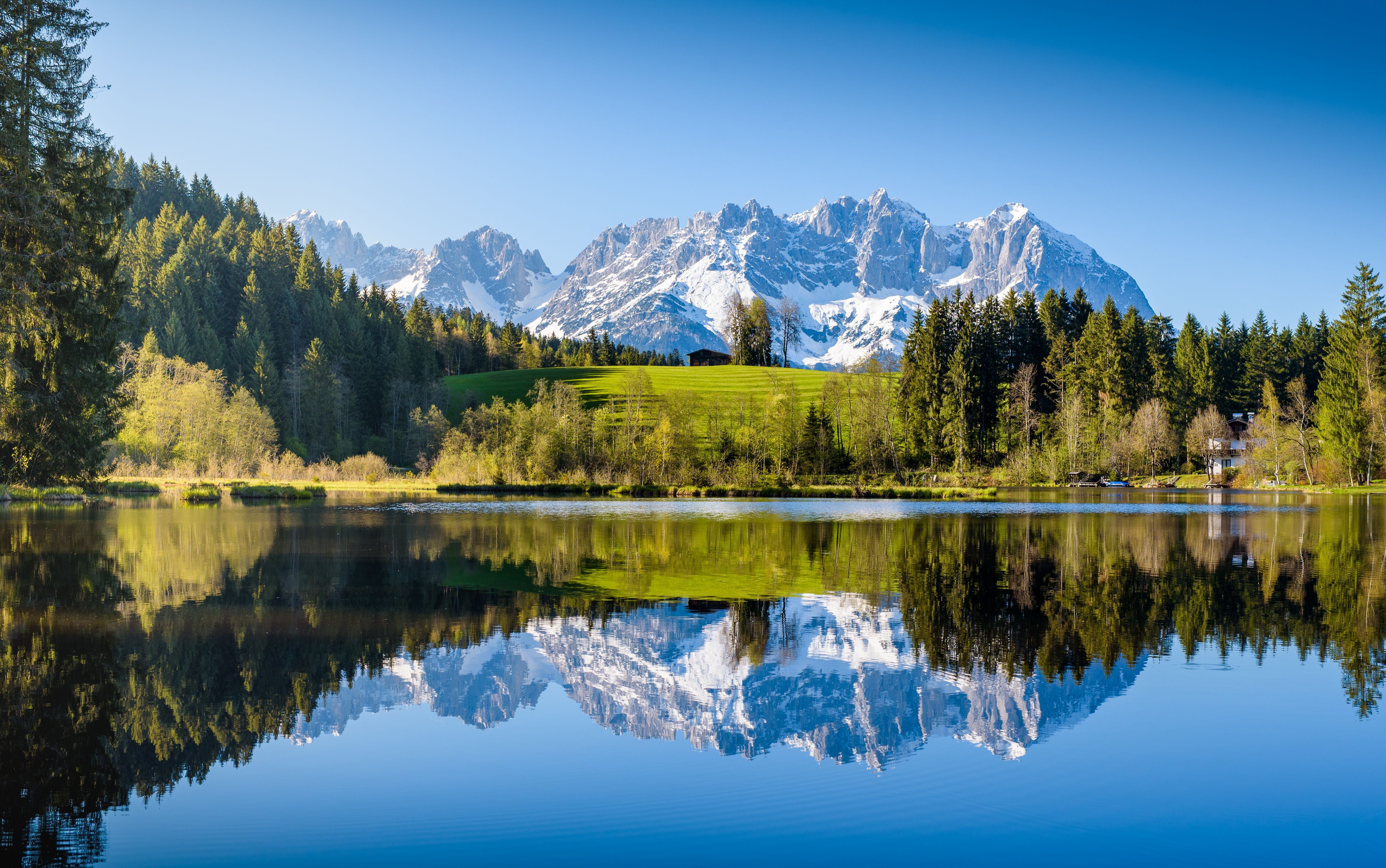 Das verschneite Wilder-Kaiser-Gebirge spiegelt sich in einem ruhigen See bei Kitzbühel.