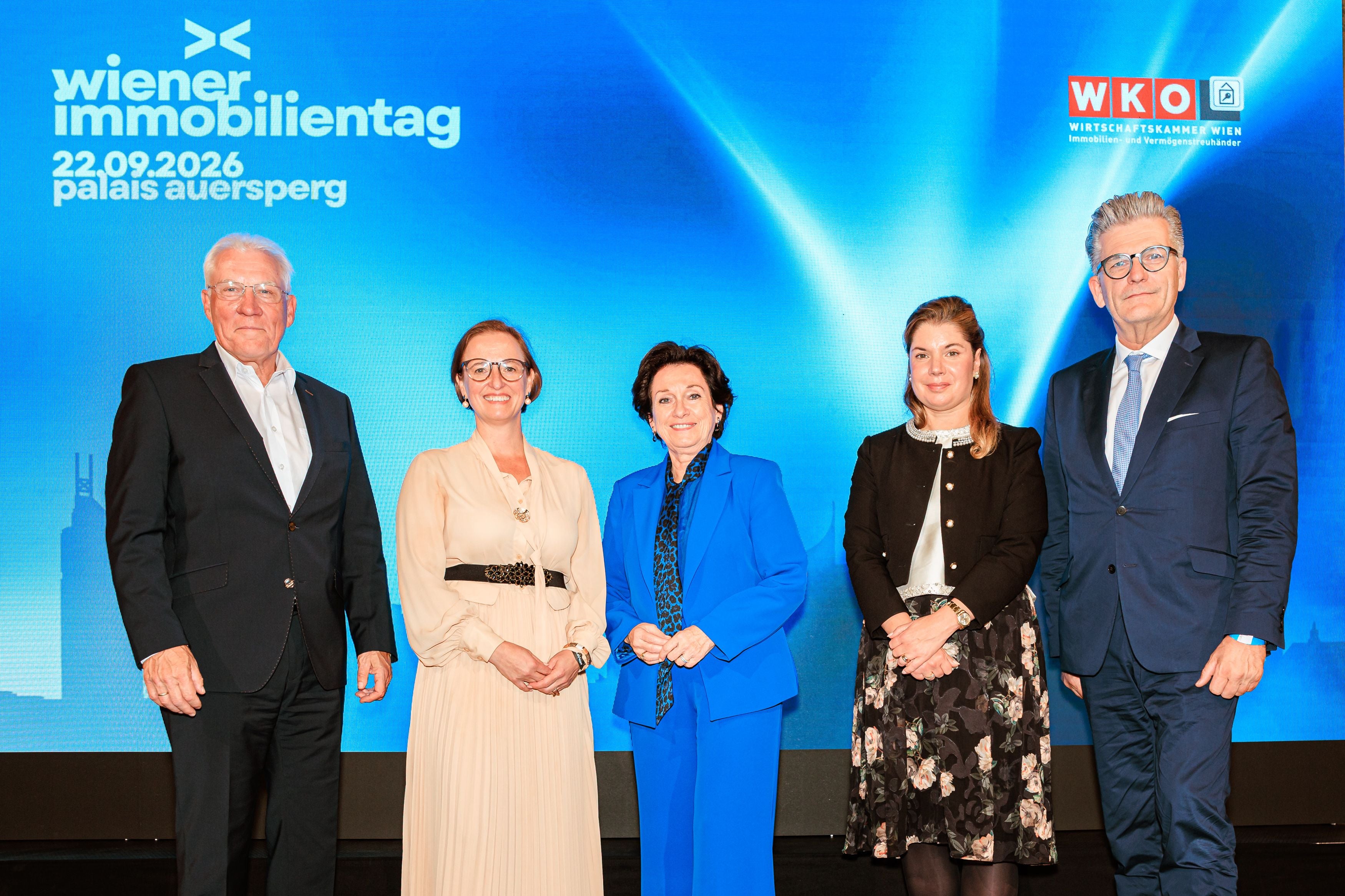 Fünf Personen stehen vor einer blauen Leinwand beim Wiener Immobilientag 2026 im Palais Auersperg.
