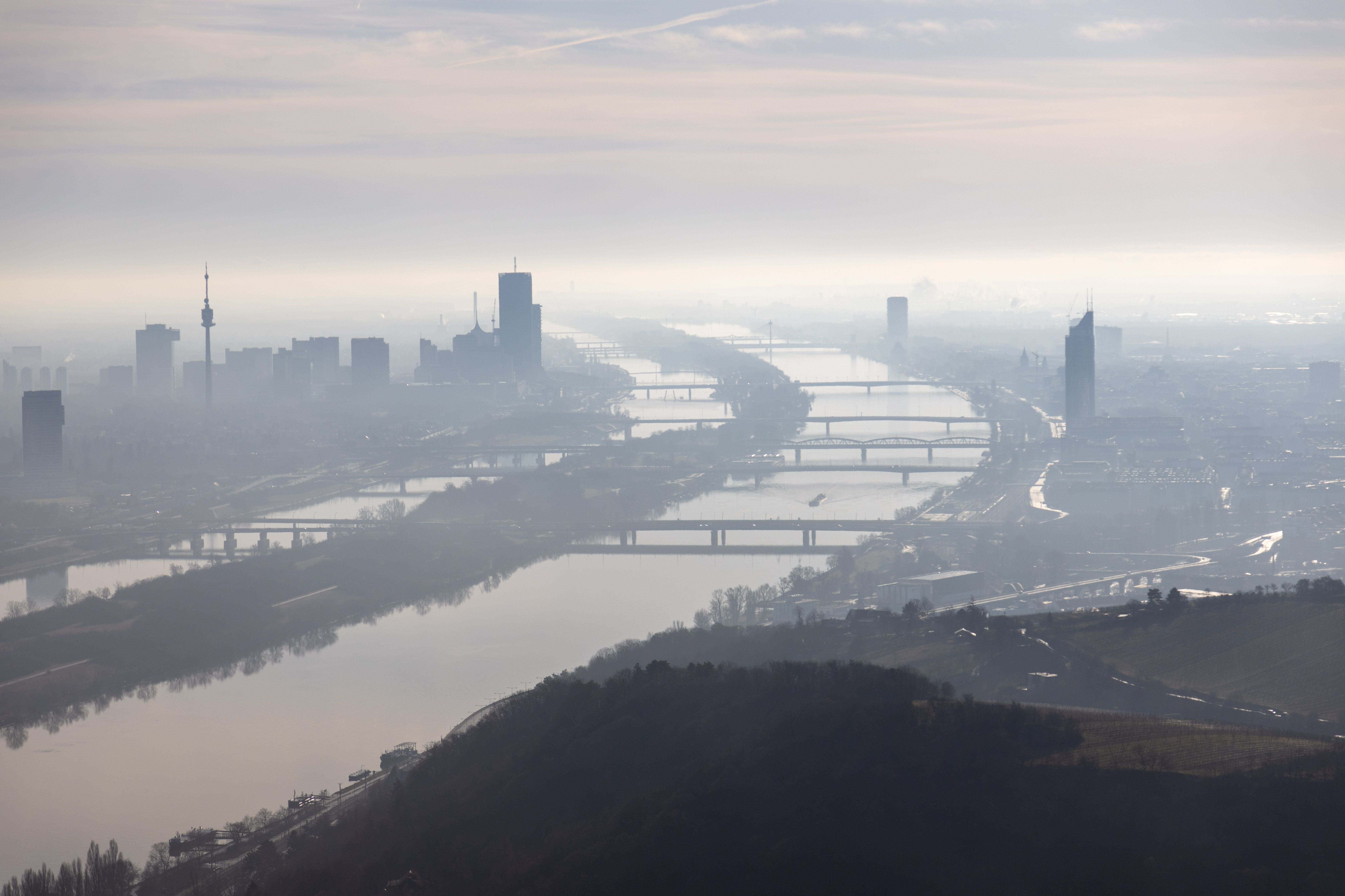 Panorama von Wien an einem nebligen Wintermorgen, Donau, Brücken und Fernsehturm sichtbar.