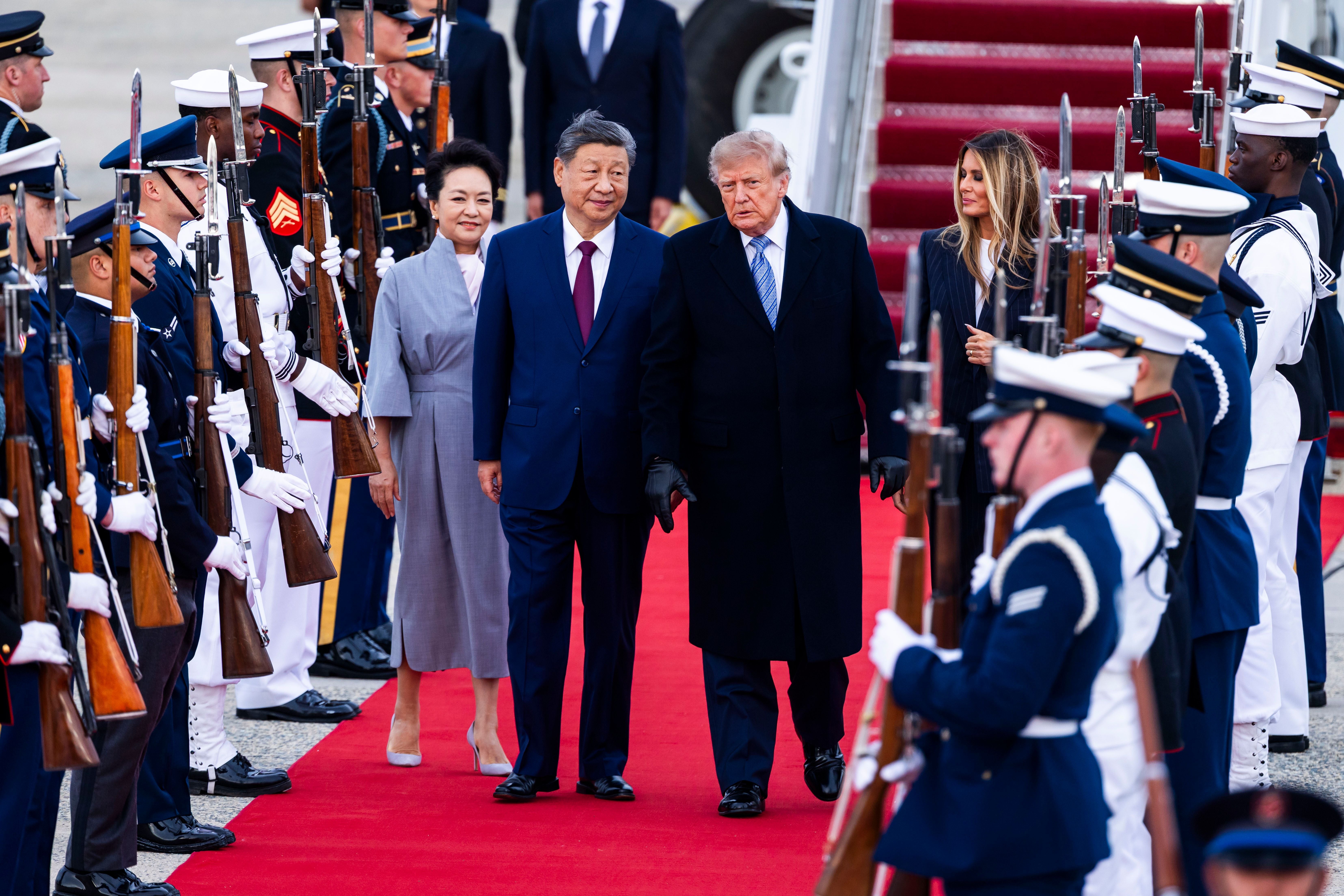 Donald Trump begrüßt Xi Jinping mit Ehefrauen auf rotem Teppich, Soldaten stehen Spalier.