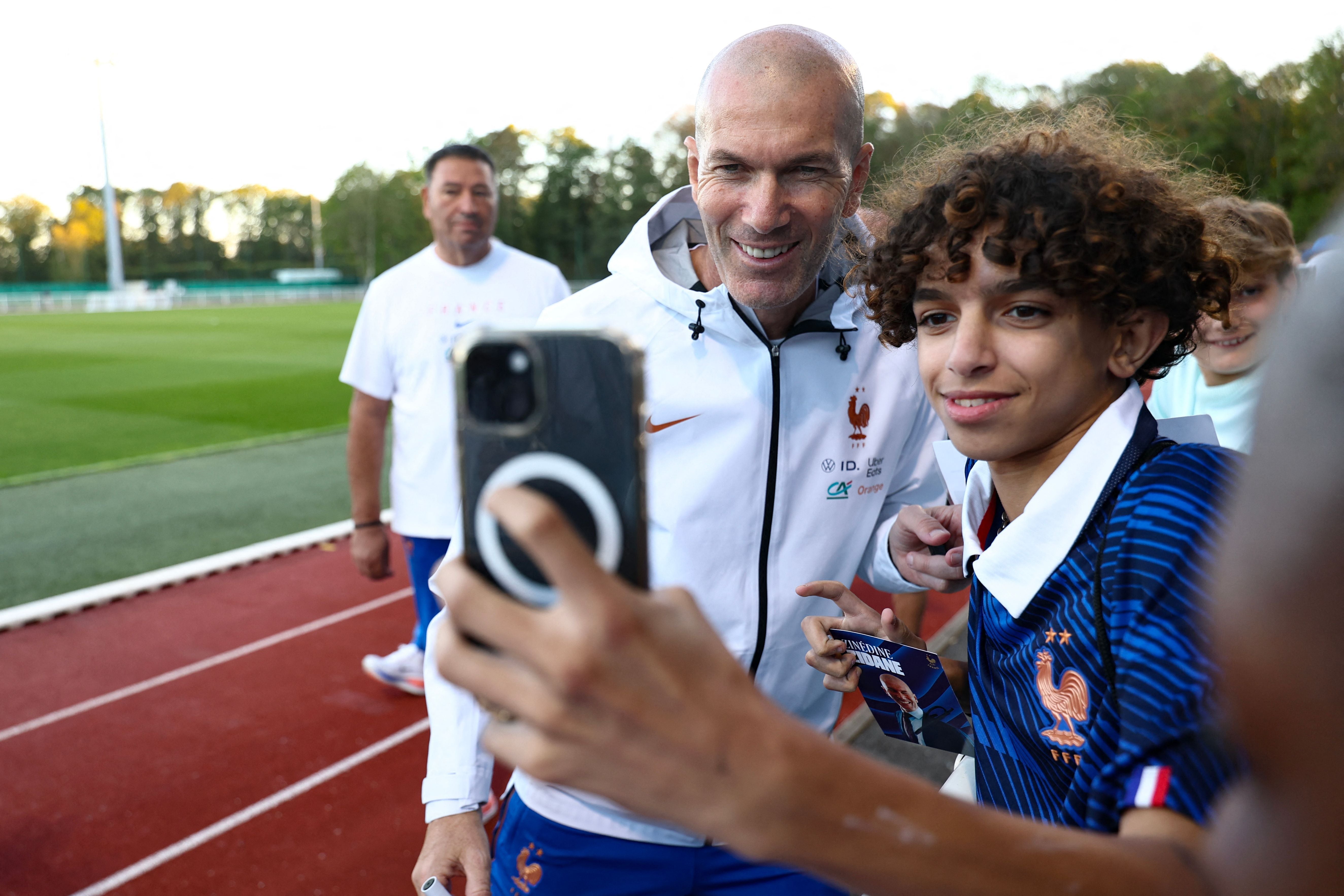 Ein Junge macht ein Selfie mit Zinedine Zidane auf einem Trainingsplatz der französischen Nationalmannschaft.