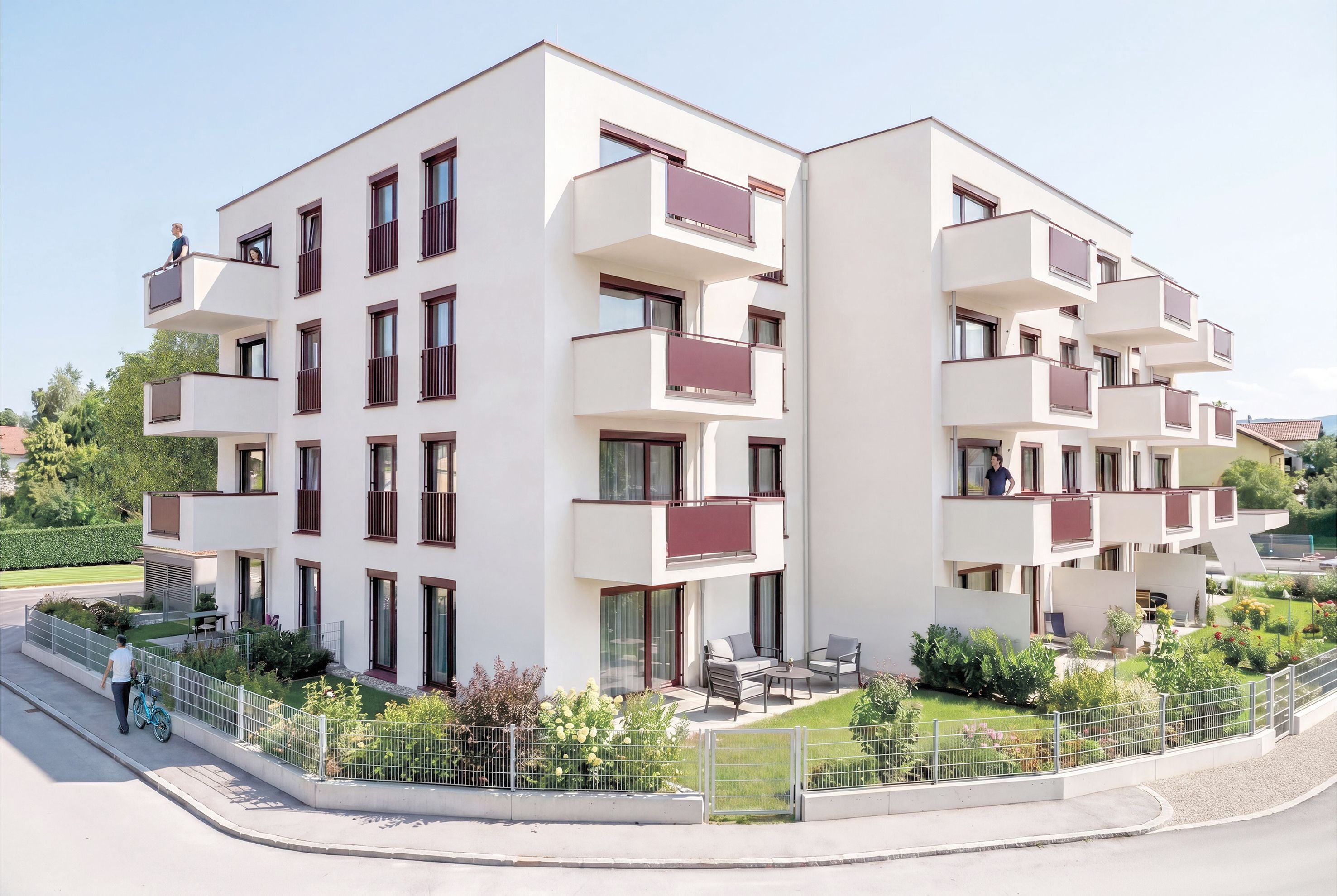 Modernes Mehrfamilienhaus mit Balkonen, Garten und mehreren Personen außen.