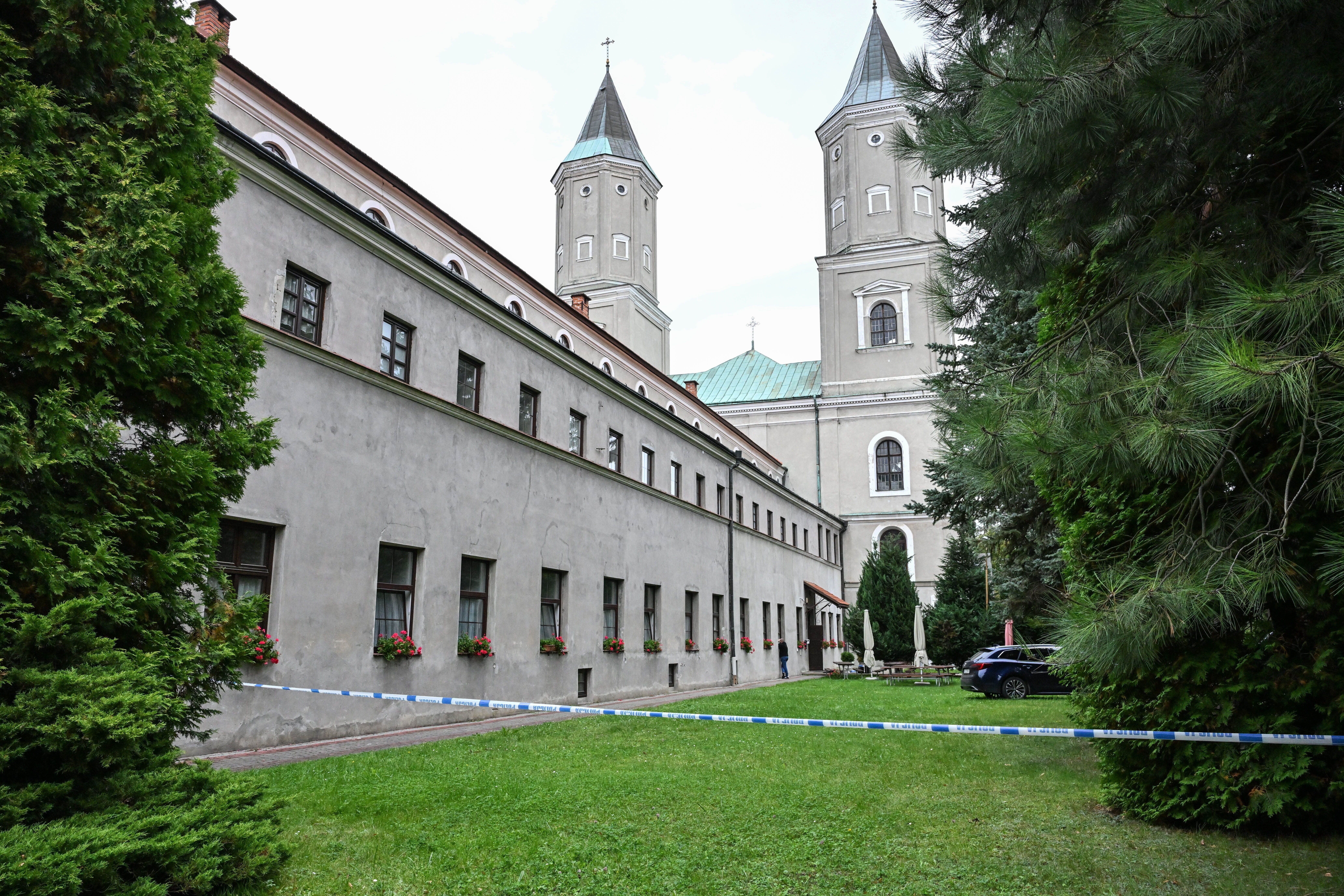 Polizeiabsperrung vor der Jaroslaw-Abtei mit Autos und Grünflächen, im Hintergrund das Klostergebäude.