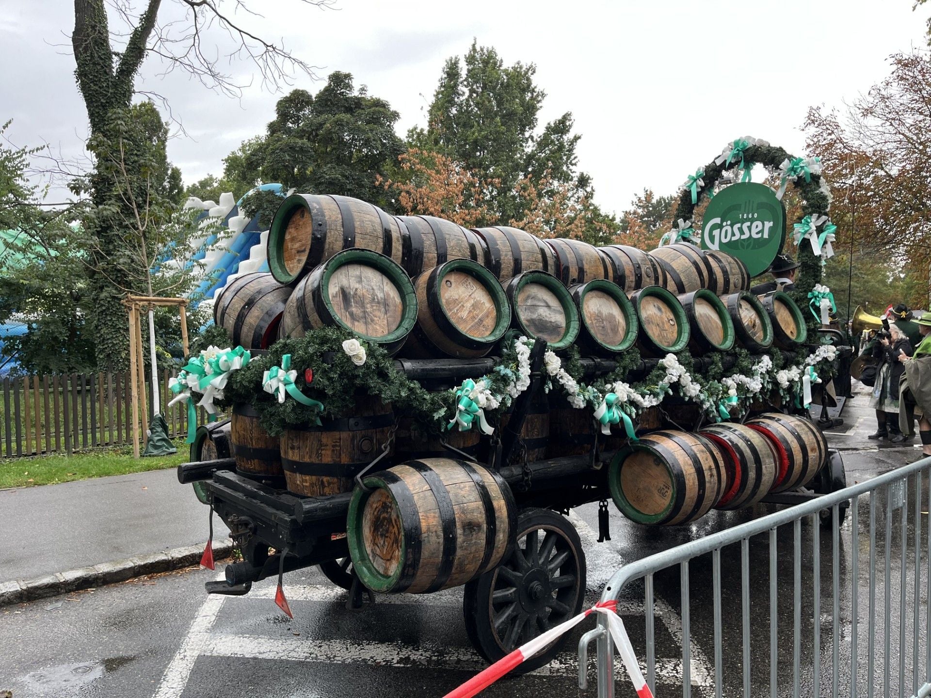 Festlich geschmückter Brauereiwagen mit vielen Holzfässern der Marke Gösser auf einer Straße.