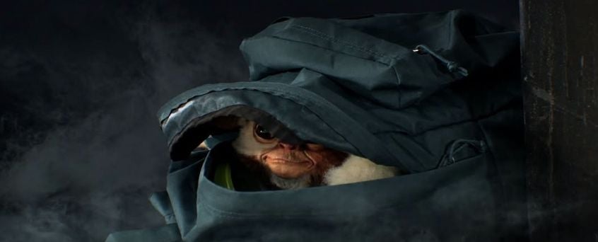 Ein Gremlin schaut aus einem teilweise geöffneten dunklen Rucksack hervor.