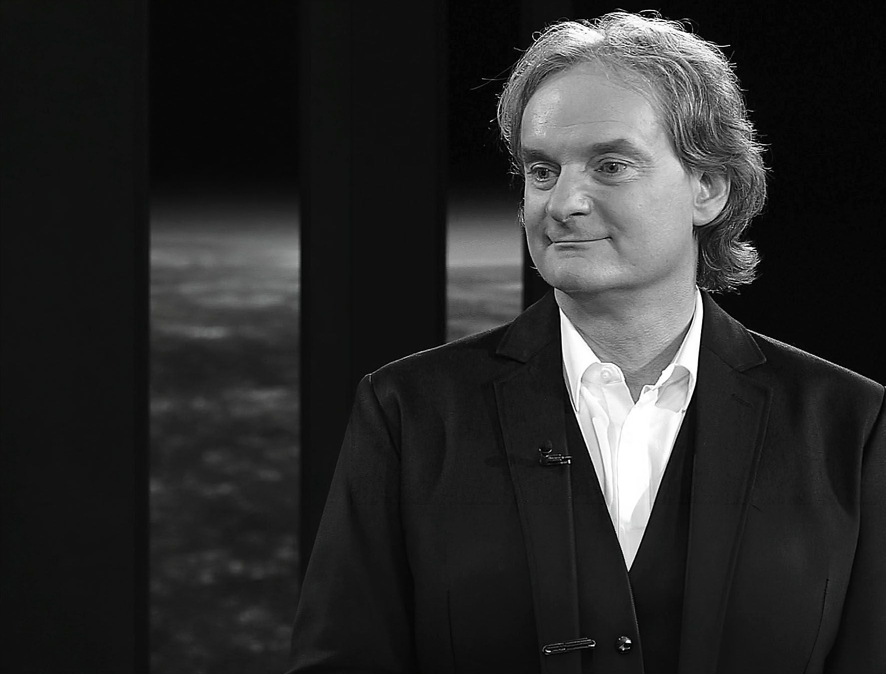 Dieter Helbig blickt in einem Schwarz-Weiß-Porträt lächelnd zur Seite.