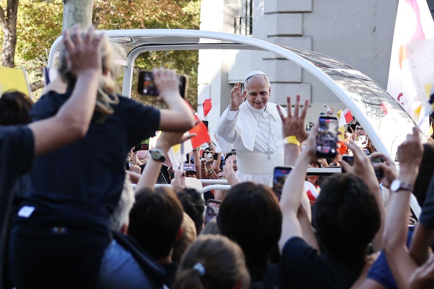 Papst winkt der jubelnden Menge aus dem Papamobil in einer Pariser Straße zu.