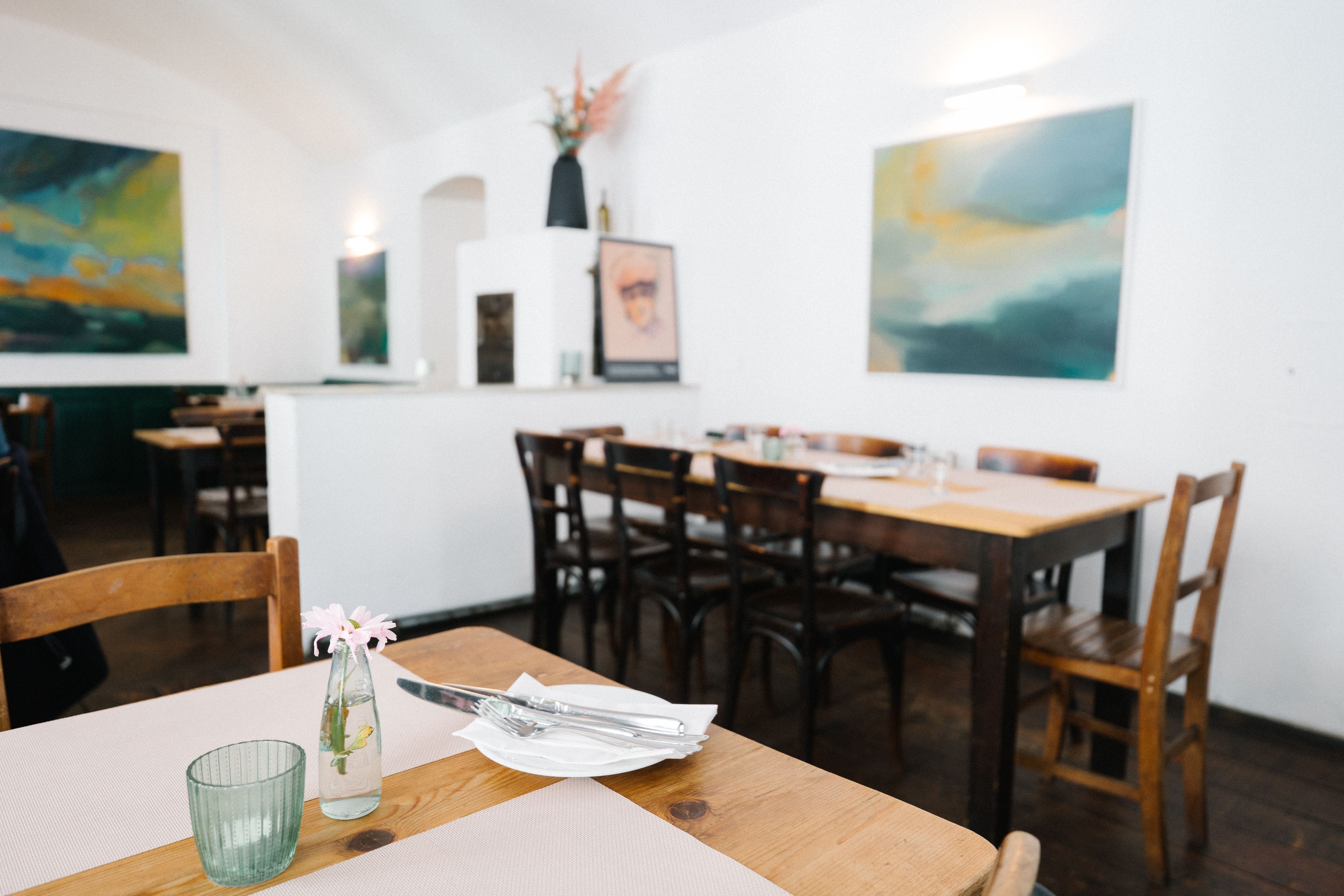 Helles, modern eingerichtetes Restaurant mit Holztischen, Stühlen und abstrakter Wandkunst.
