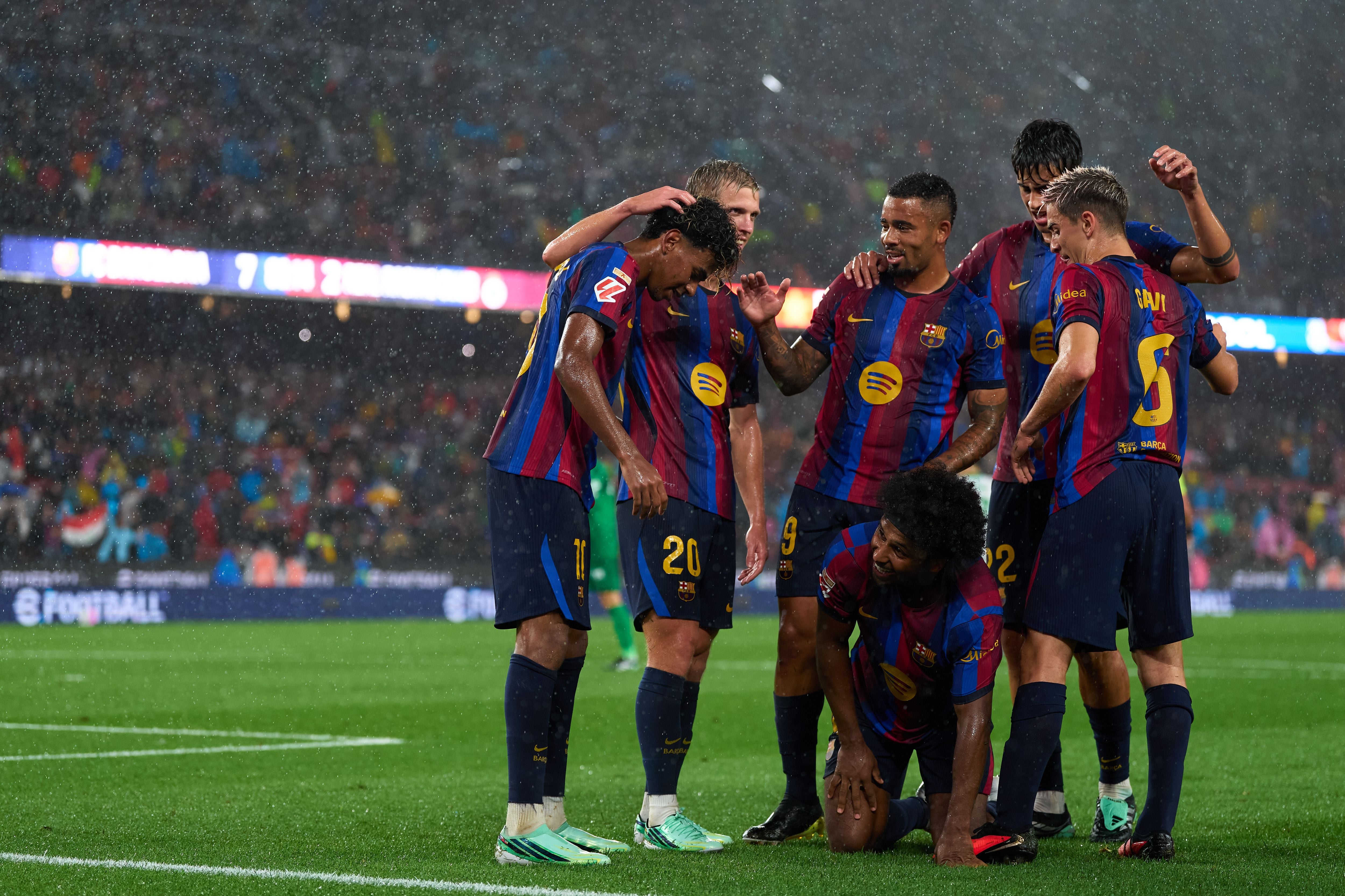 FC-Barcelona-Spieler feiern ein Tor bei Regen im Stadion während eines Fußballspiels.