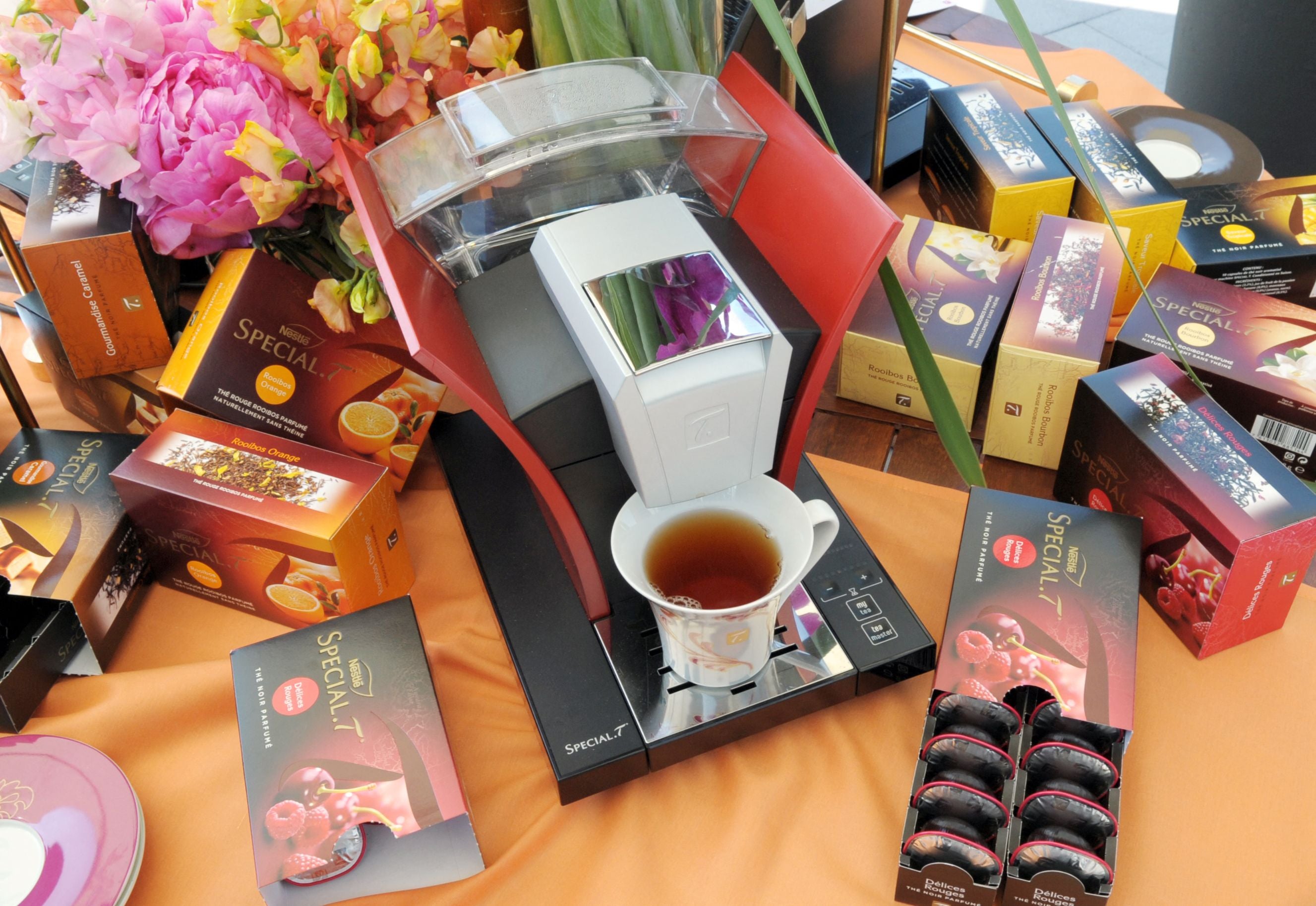 Eine Nestlé Special.T Teemaschine mit Teetasse, Teekapseln und Teeverpackungen auf einem Tisch.
