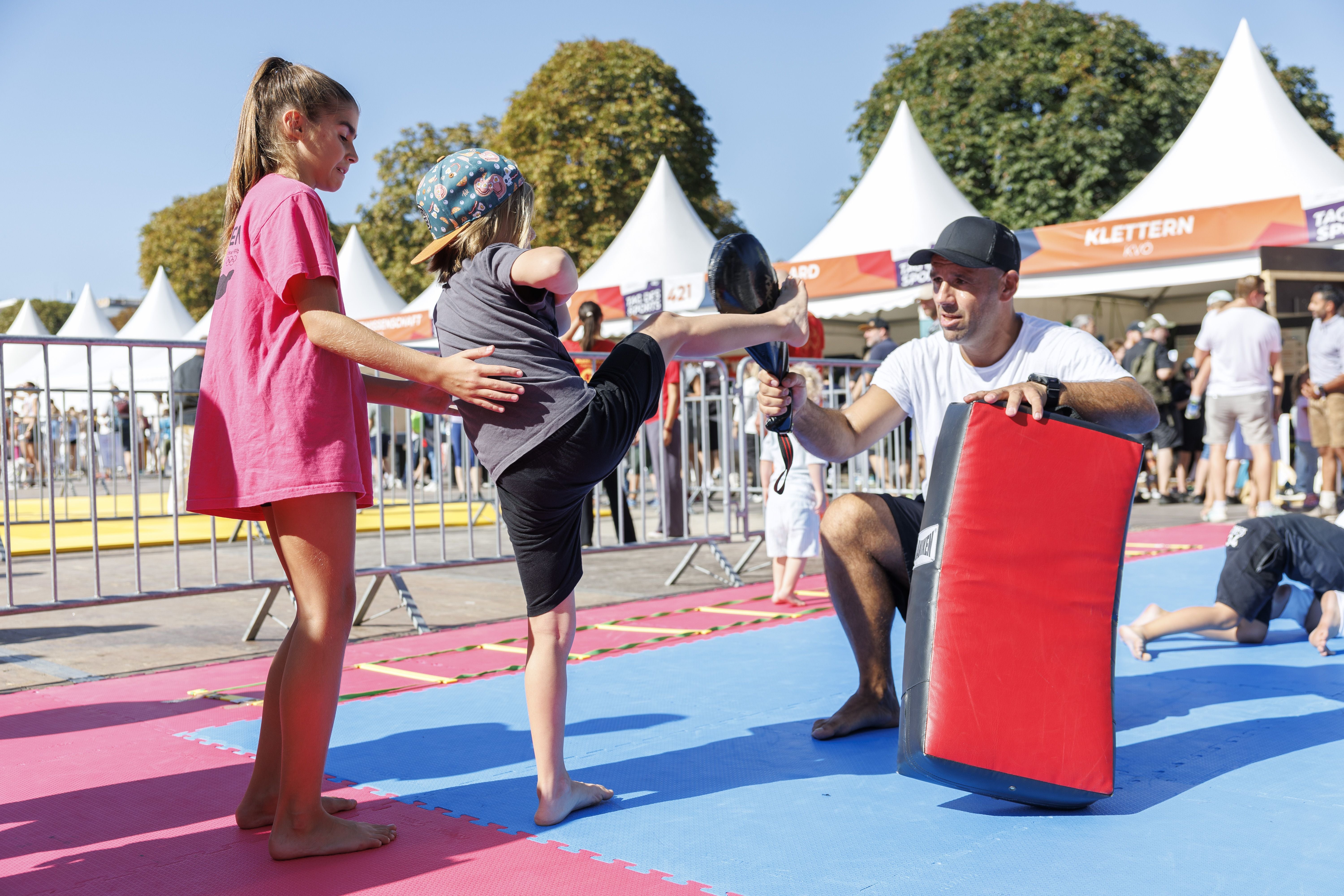 Kinder üben Kampfsport mit Trainer im Freien am Tag des Sports in Wien.