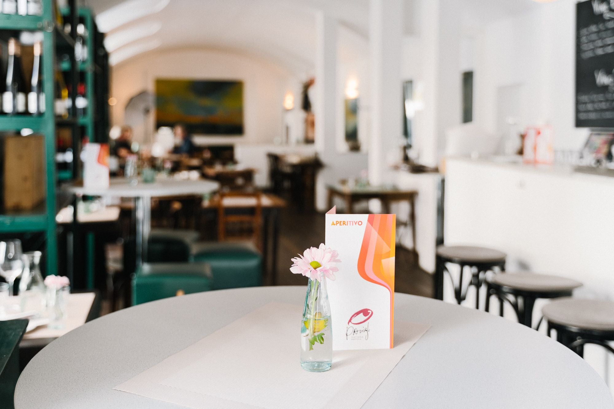 Eine Menükarte und eine Blume in einer Vase stehen auf einem Tisch in einem modernen Restaurant.