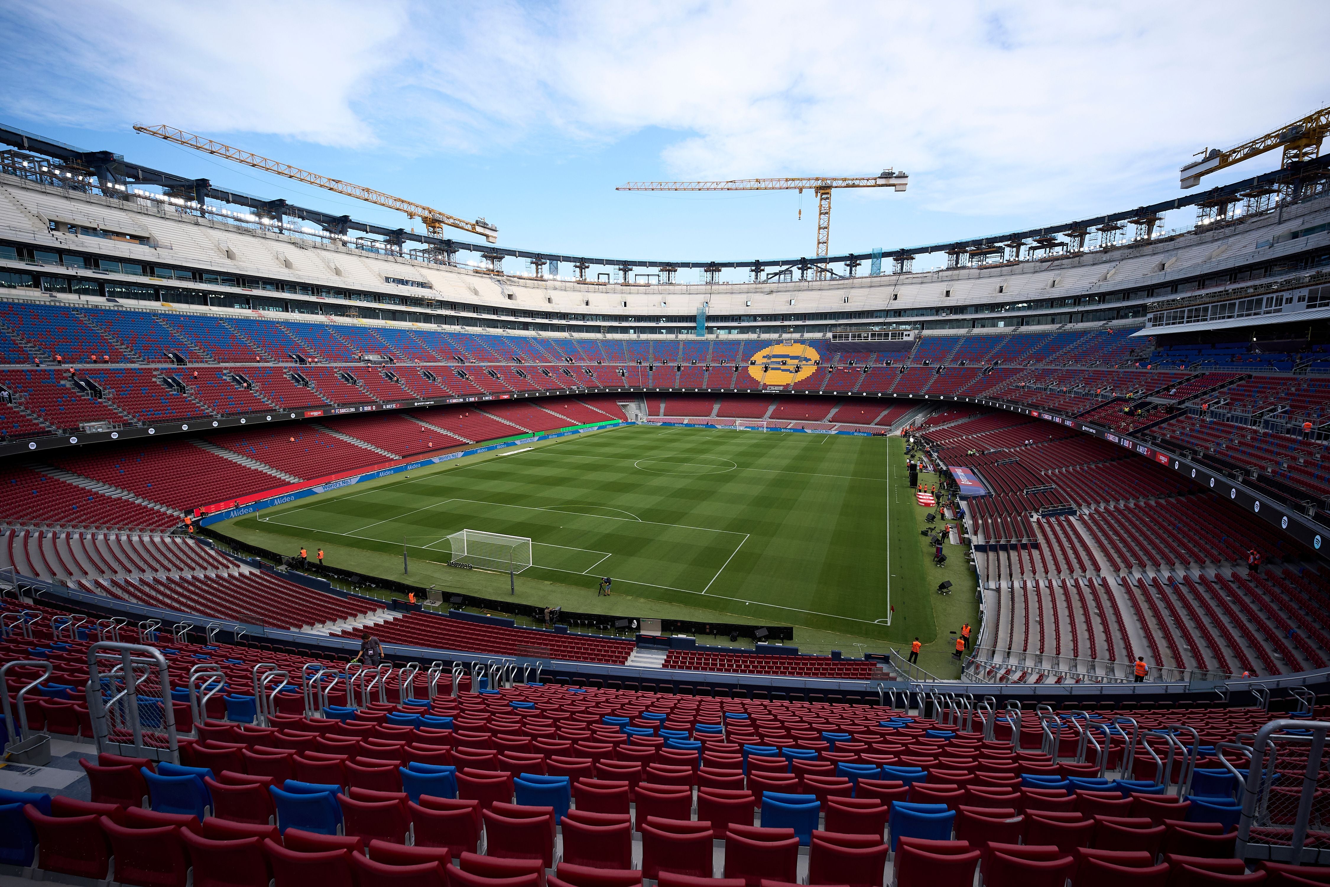 Leeres Fußballstadion Spotify Camp Nou in Barcelona mit sichtbaren Baukränen und bunten Sitzreihen.