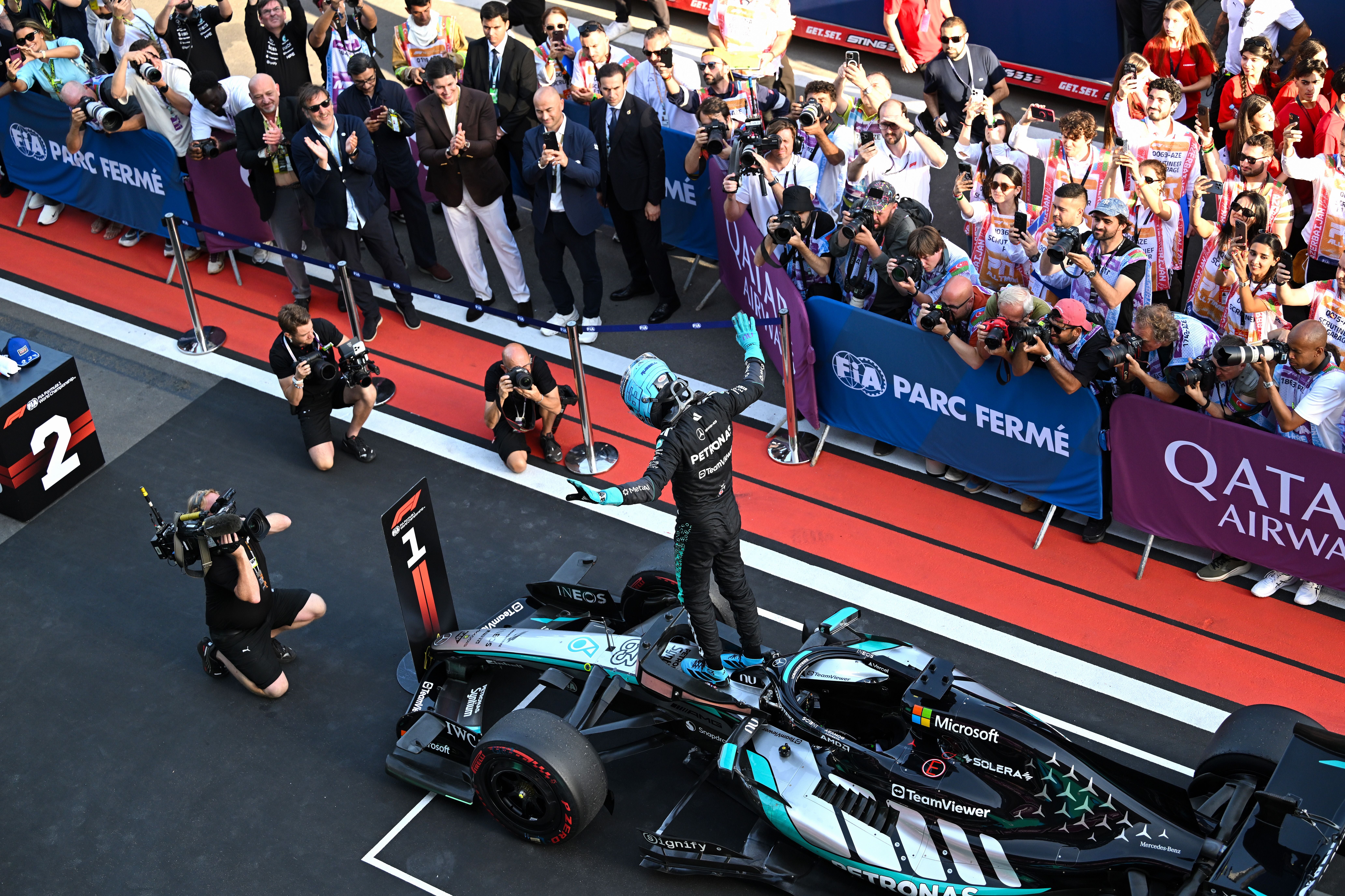Ein Mercedes-F1-Fahrer feiert im Parc Fermé vor jubelnden Fans und vielen Fotografen.