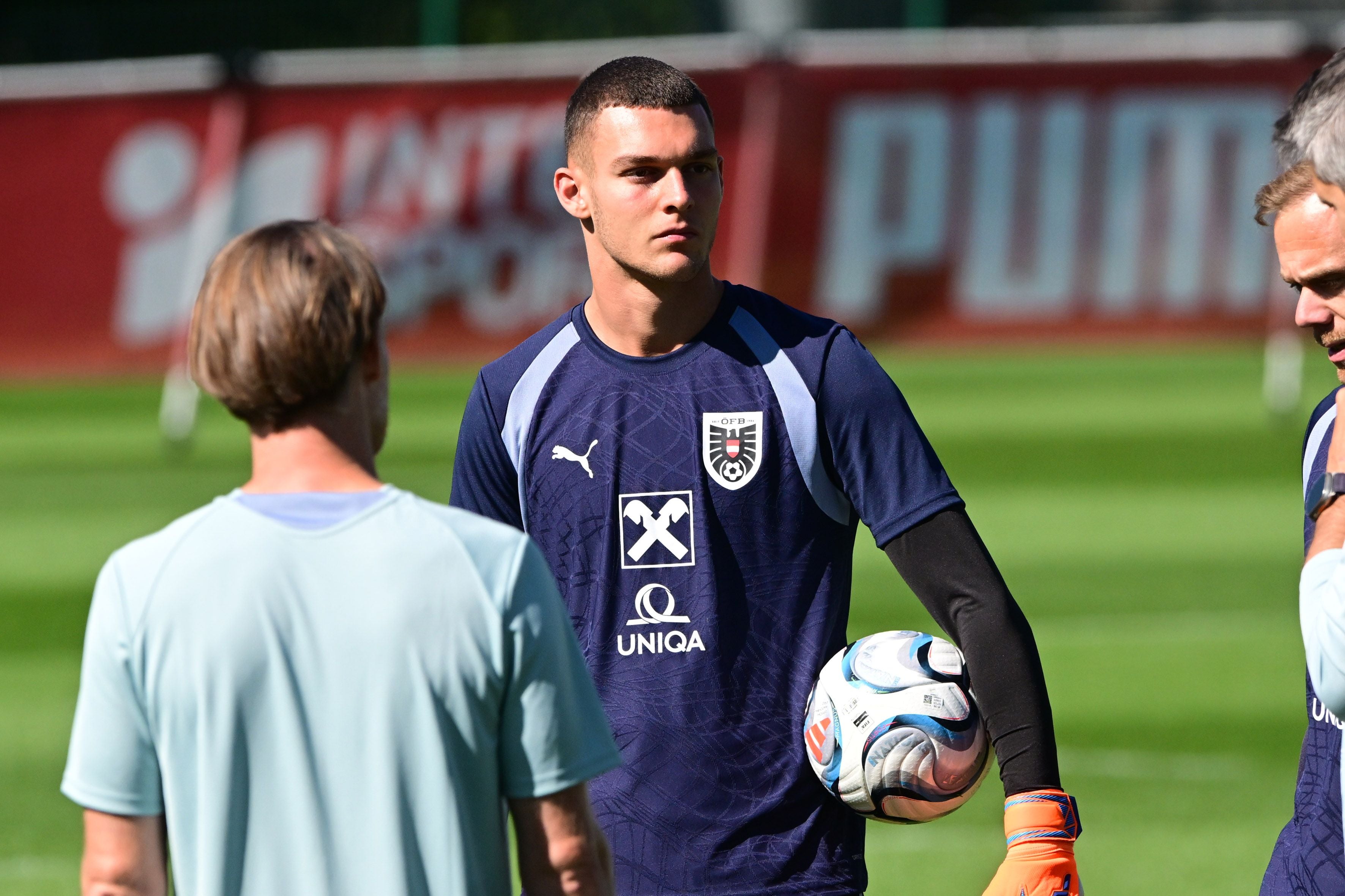 Torwart im Trainingsoutfit hält Fußball beim Training des österreichischen Nationalteams auf dem Spielfeld.