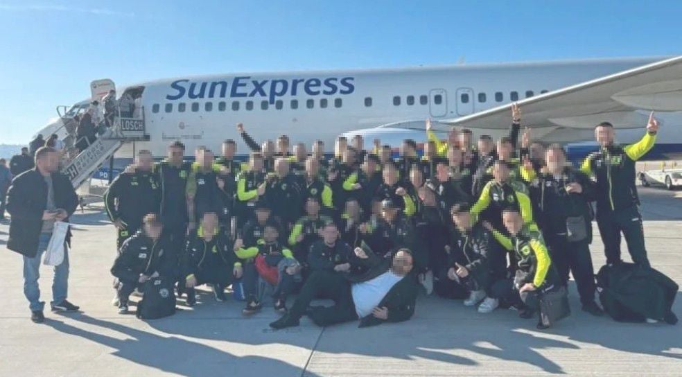 Eine große Fußballmannschaft posiert vor einem SunExpress-Flugzeug am Flughafen.