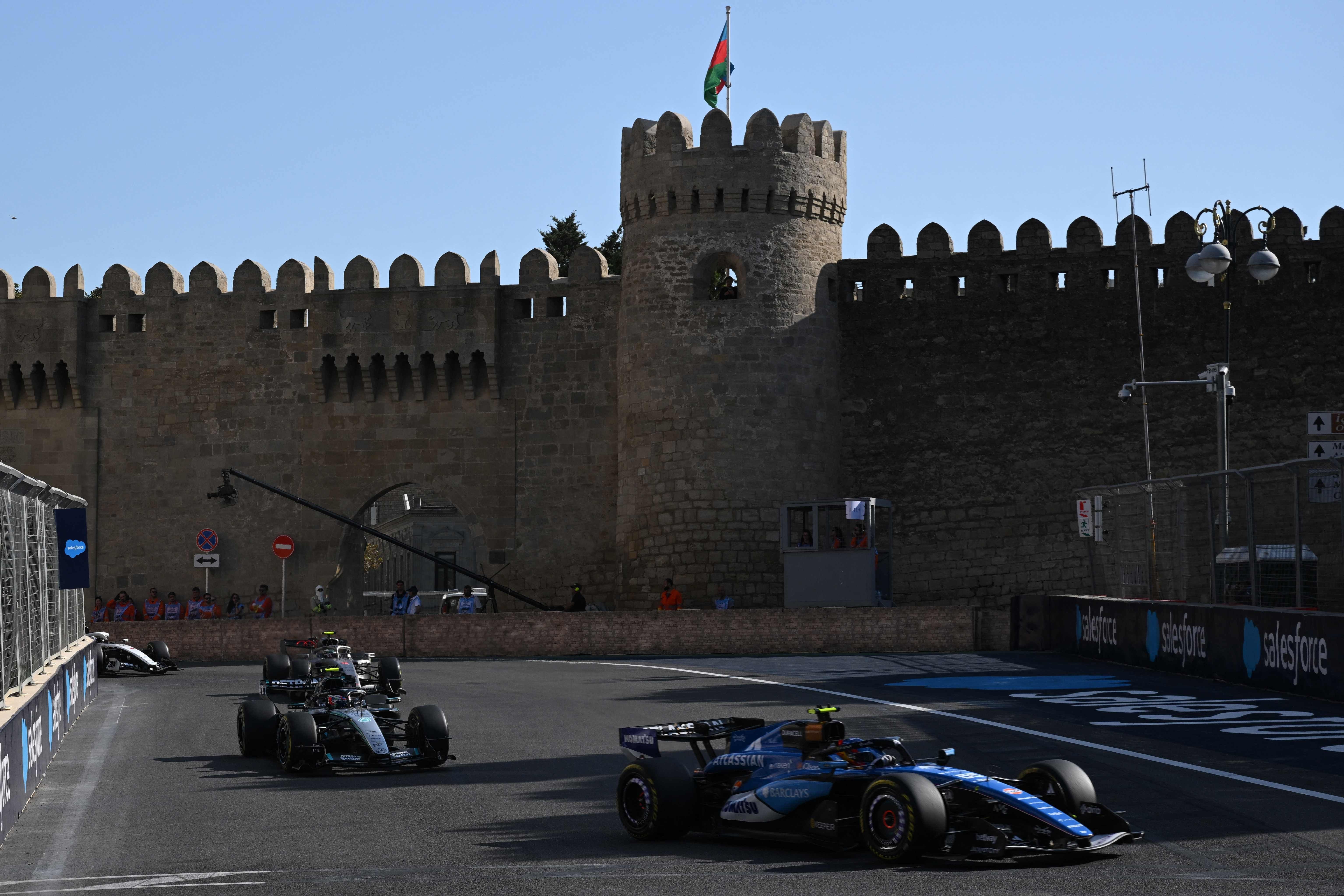 Formel-1-Autos fahren am Baku City Circuit vor einer alten Festungsmauer entlang.