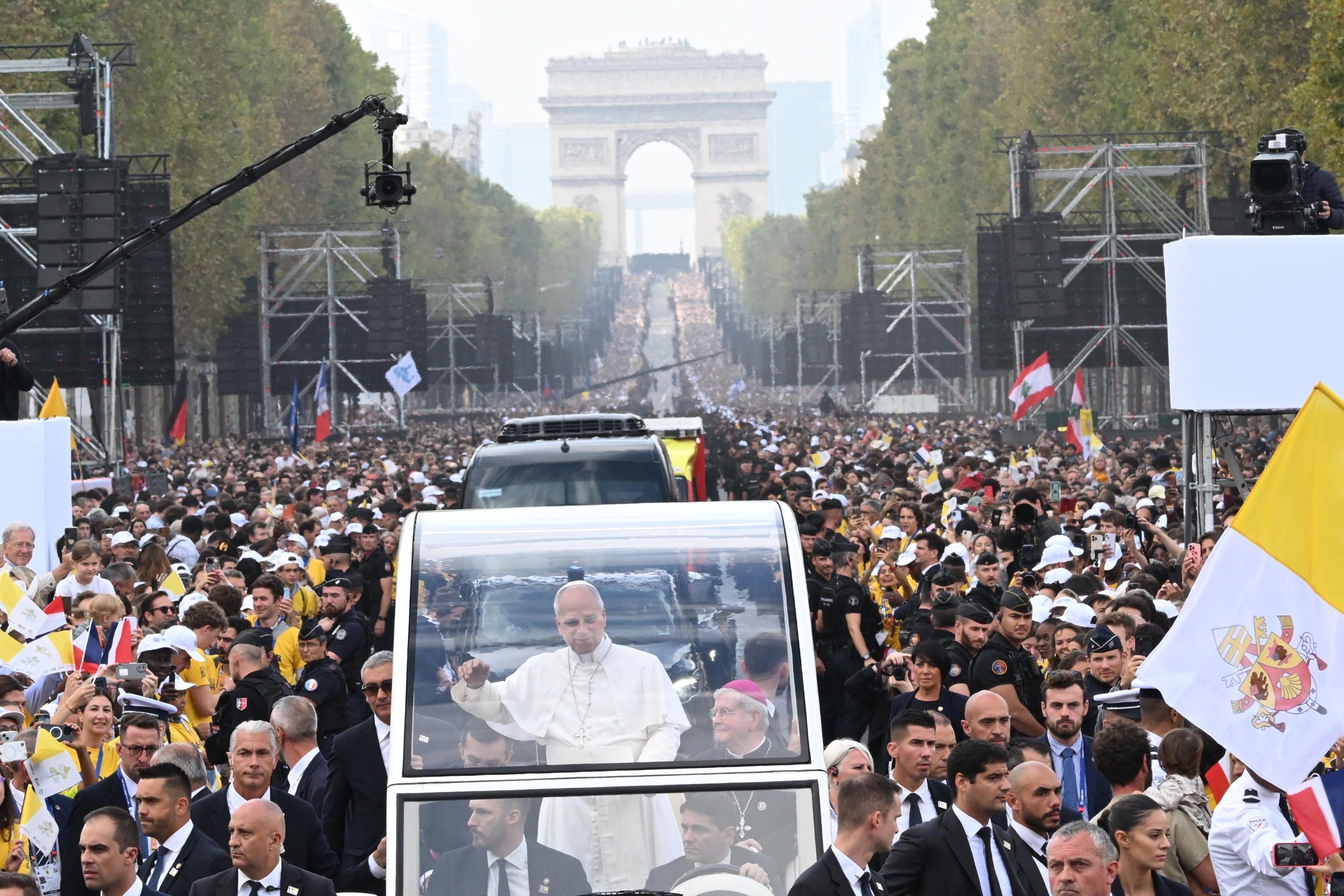 Papst Leo XIV. fährt im Papamobil durch Menschenmengen in Paris mit dem Arc de Triomphe im Hintergrund.
