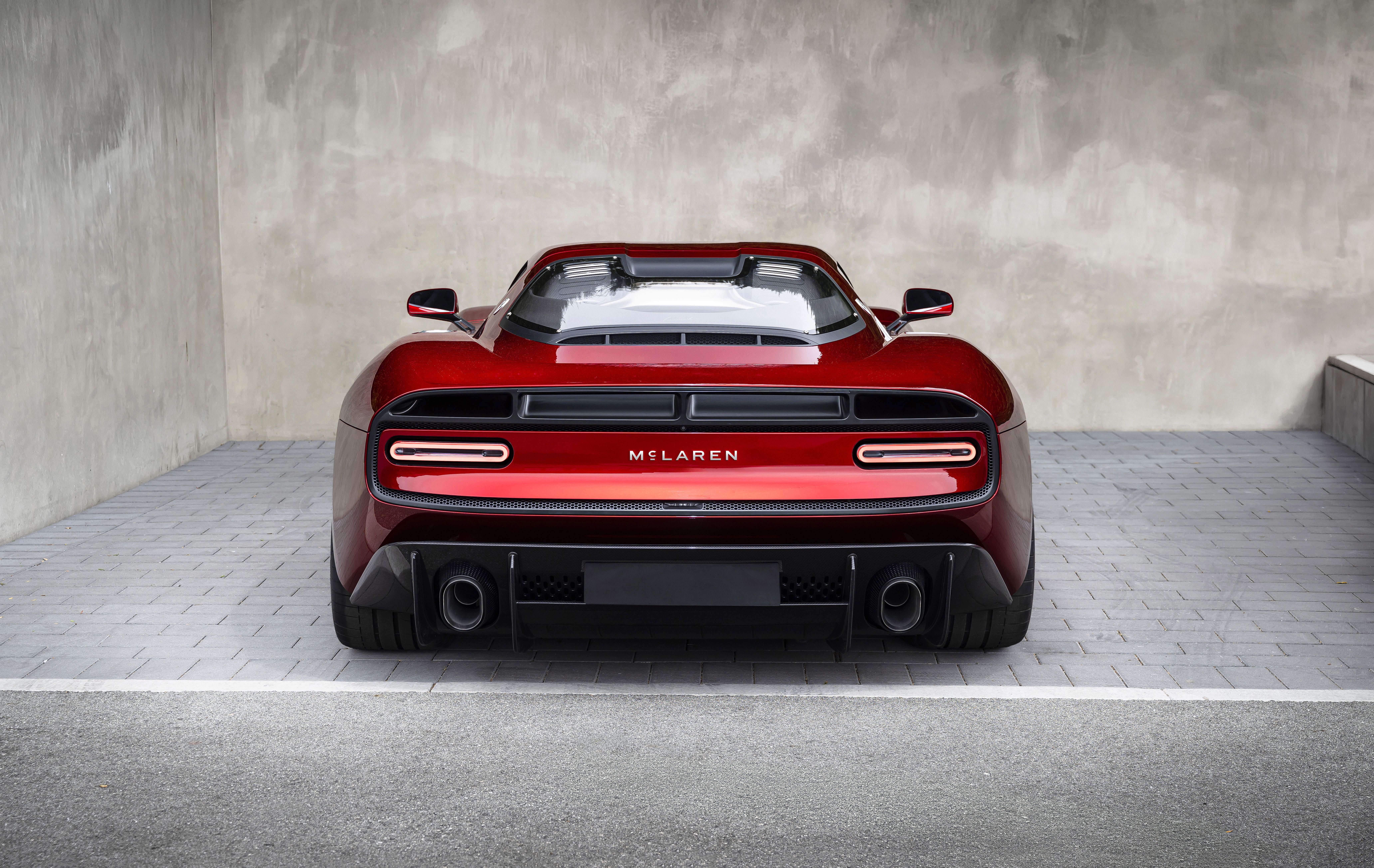 Rotes McLaren-Sportwagen-Heck vor grauer Betonwand.