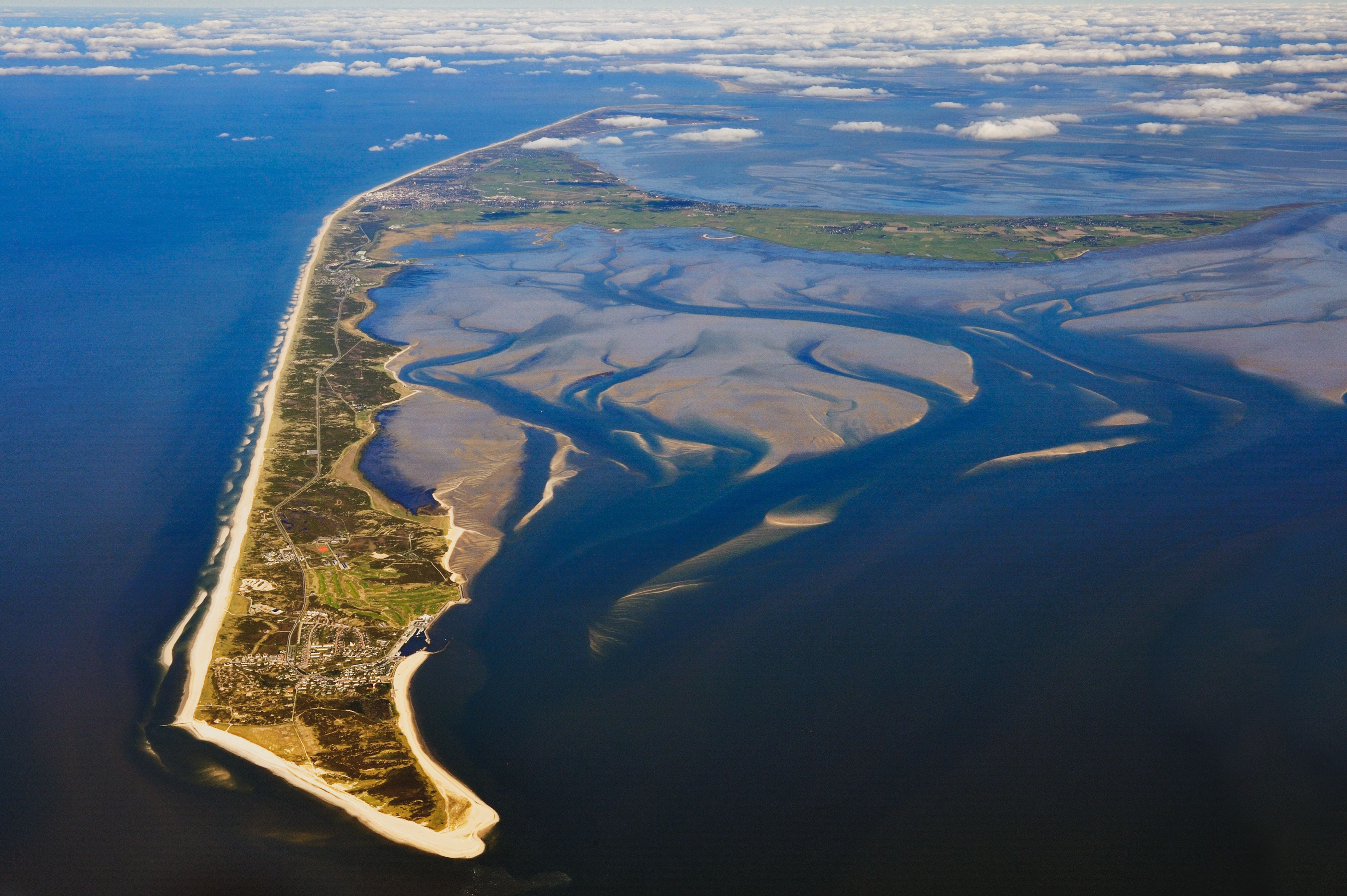 Luftaufnahme von Sylt mit Sandstränden, Ortschaften und dem Wattenmeer an der Nordseeküste.