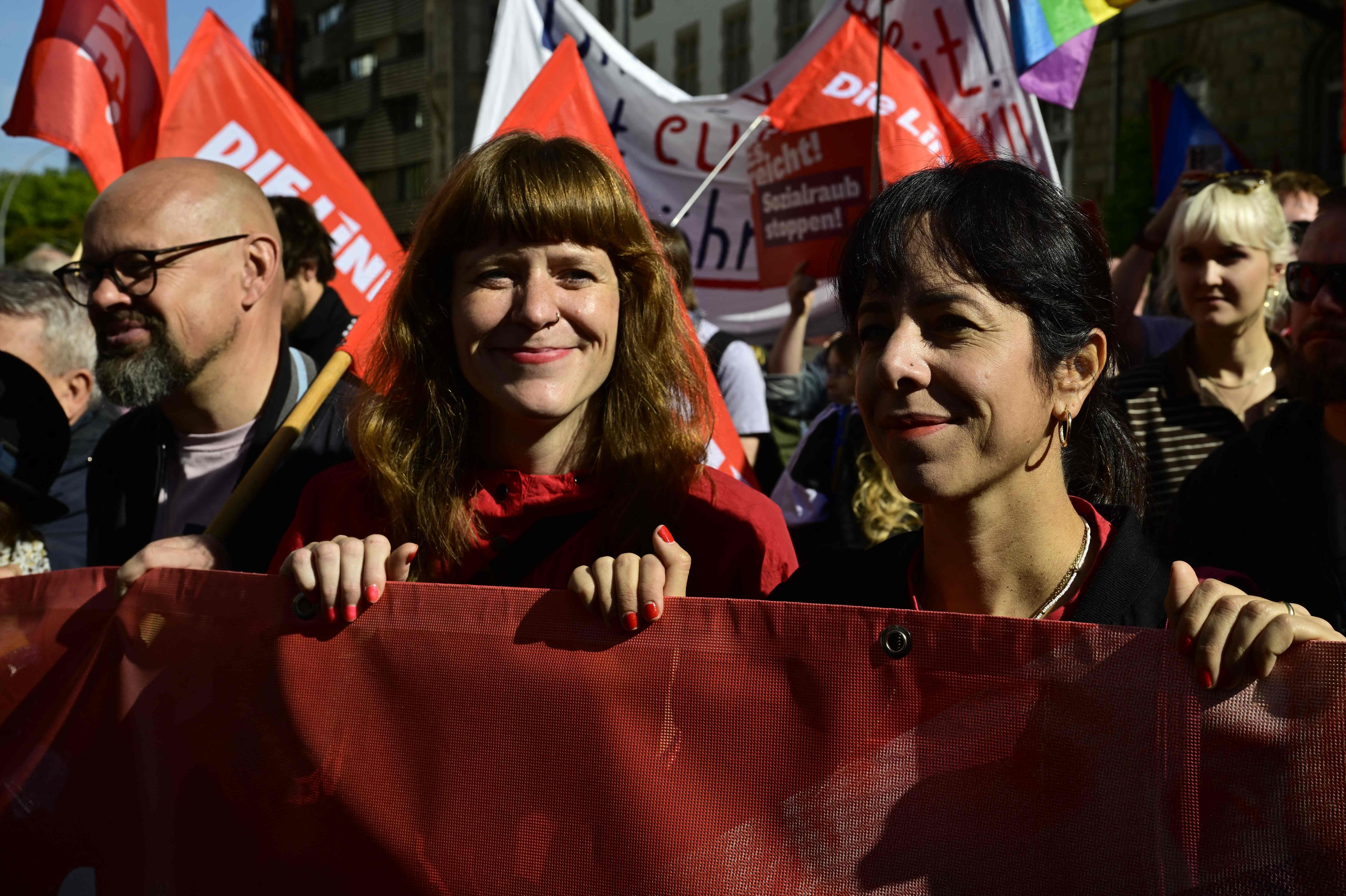Menschen mit roten Fahnen und Transparenten nehmen an einer Protestkundgebung in Berlin teil.