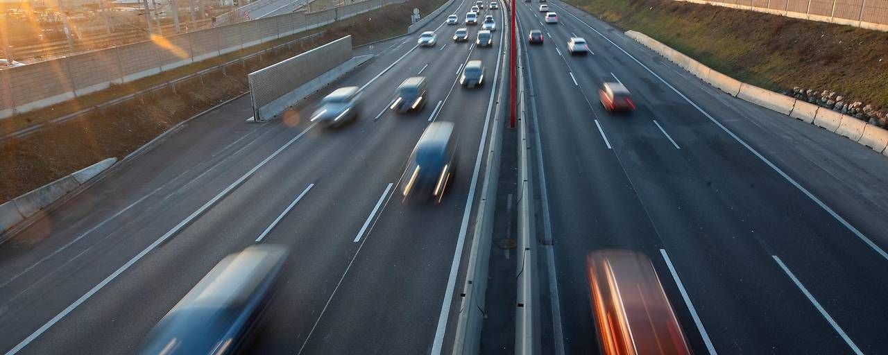 Autos fahren schnell auf einer mehrspurigen Autobahn bei Sonnenuntergang.