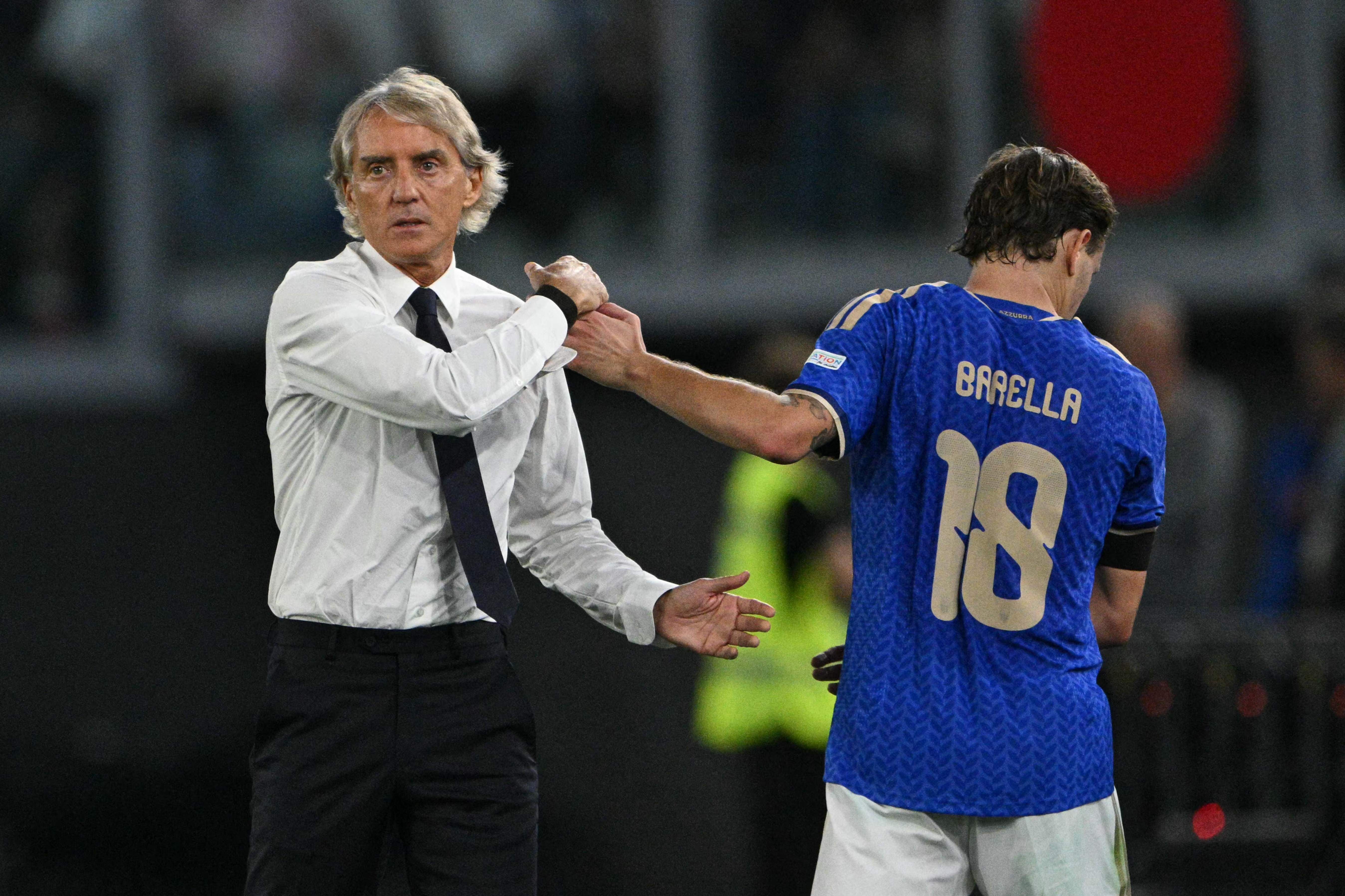 Roberto Mancini greift Nicolò Barella im blauen Italien-Trikot am Handgelenk.