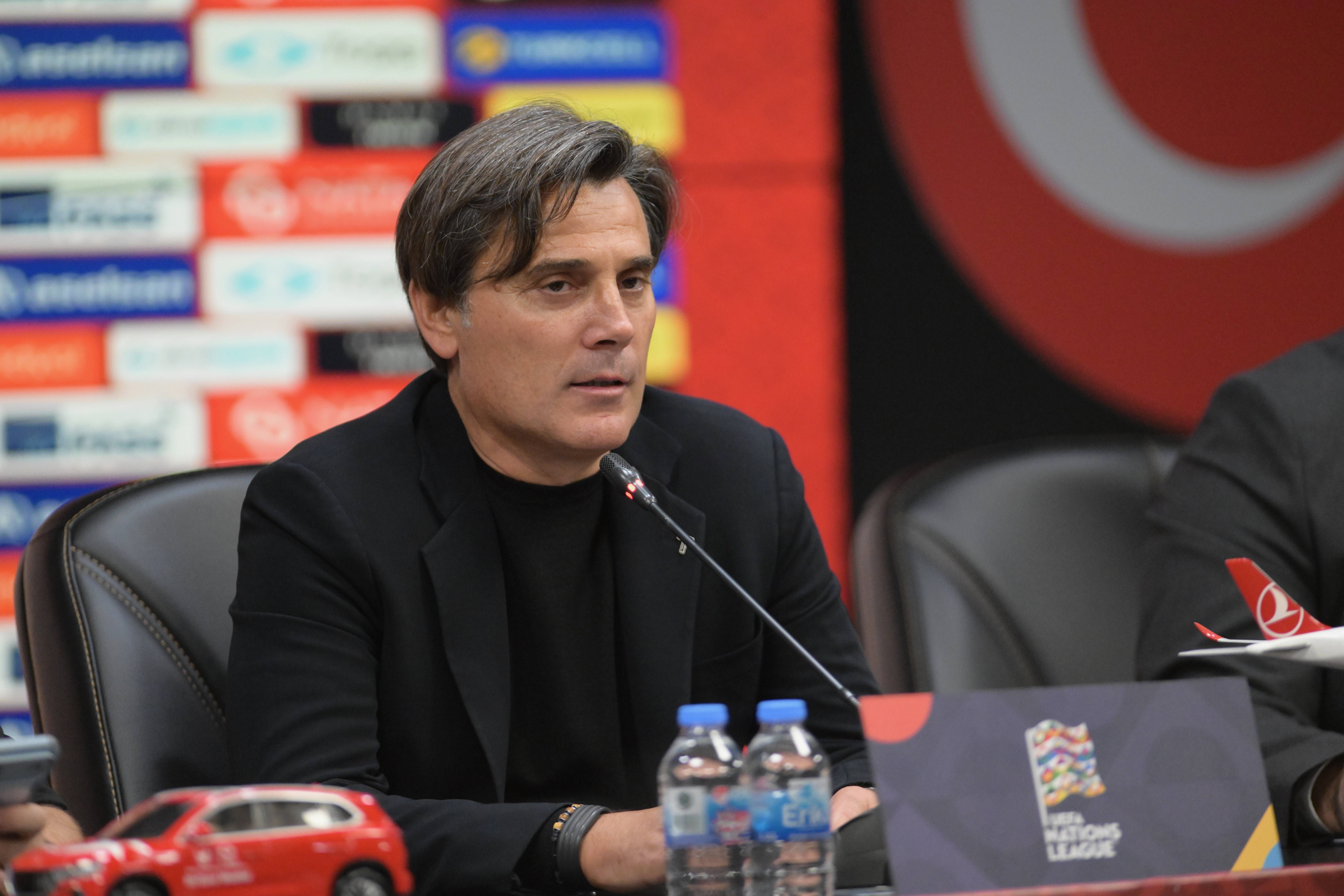 Vincenzo Montella sitzt im dunklen Sakko und Rollkragenpullover bei einer Pressekonferenz hinter Mikrofonen.