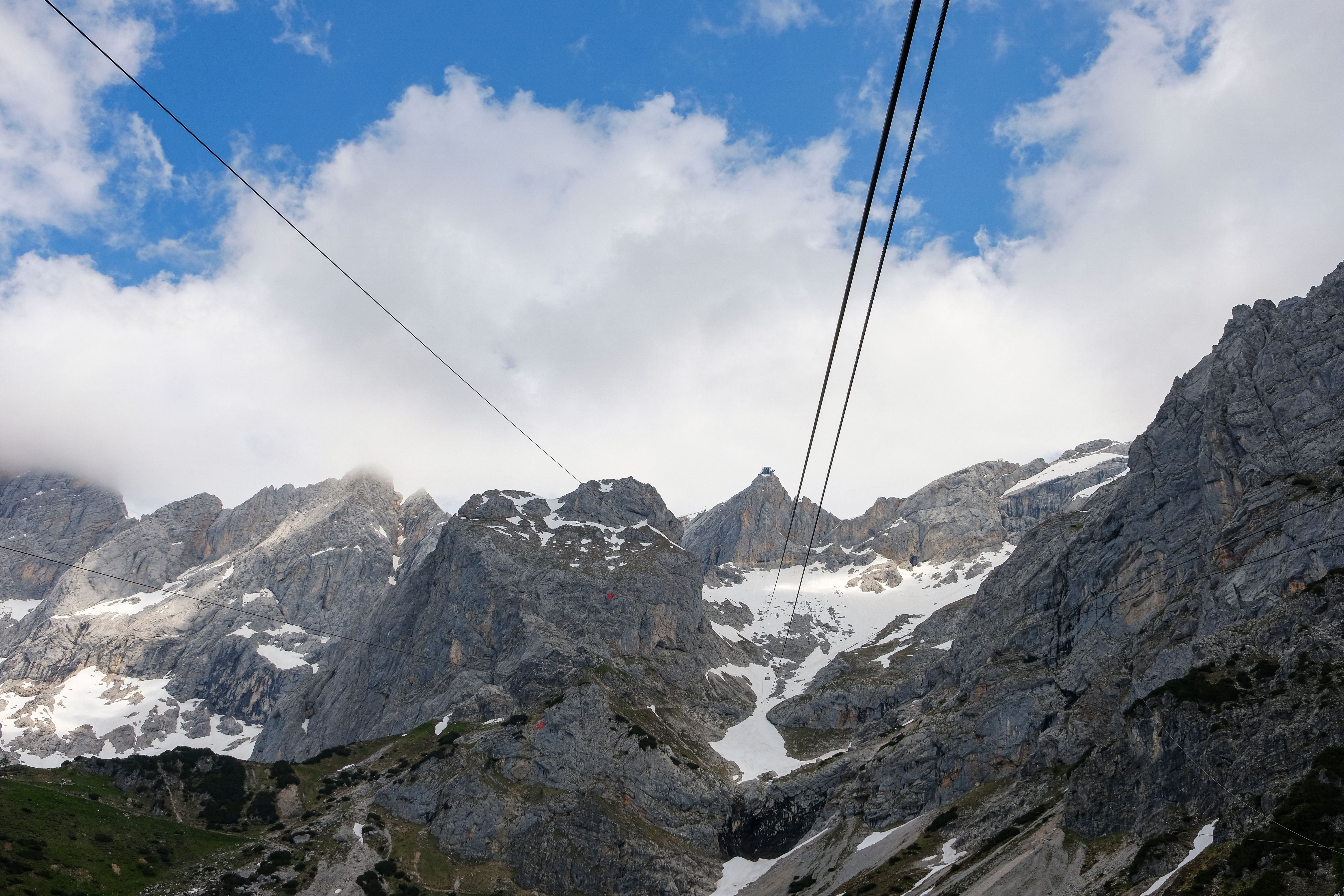 Seilbahnkabel führen über verschneite Felsen des Dachstein-Gletschers unter blauem Himmel.