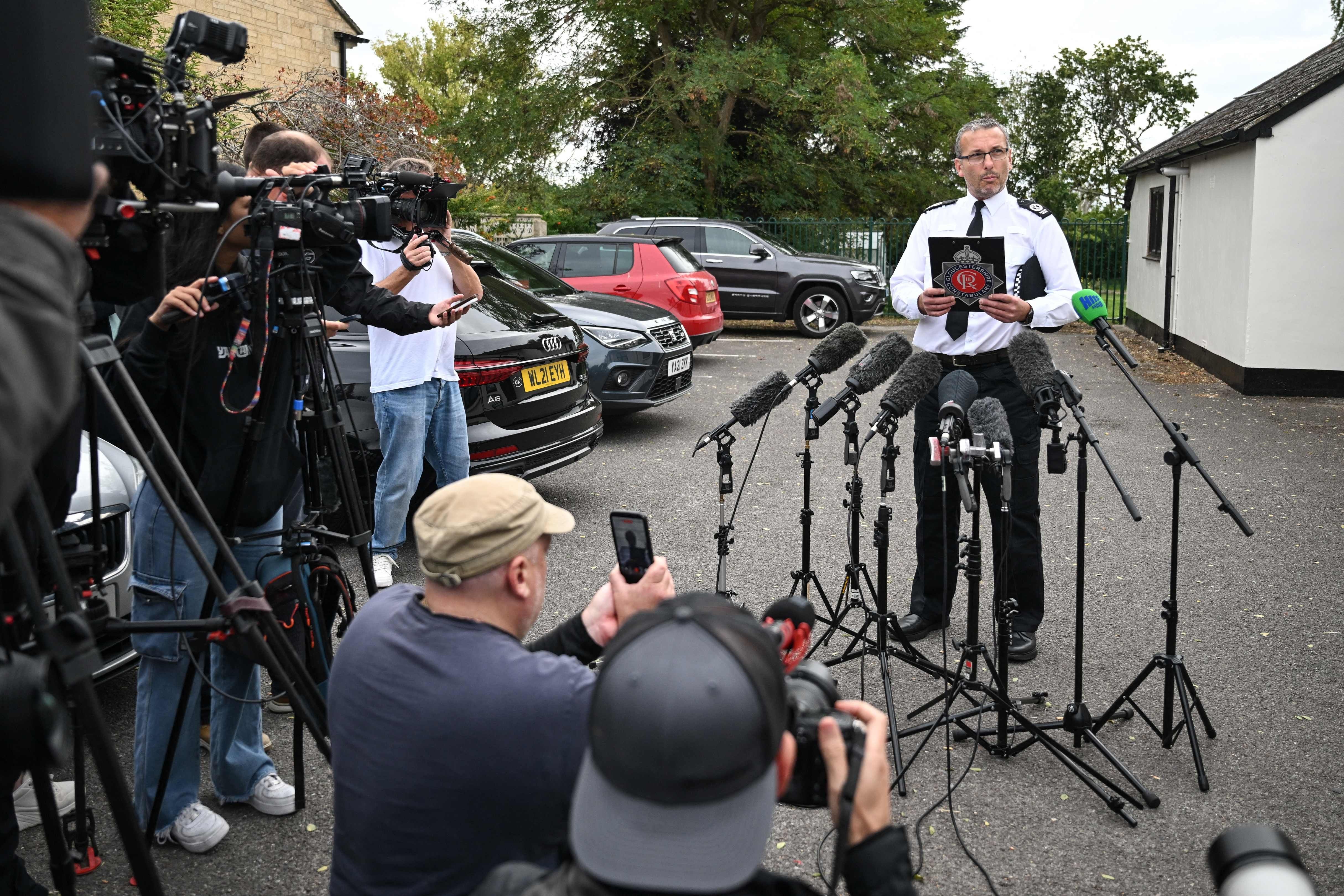 Ein Polizeibeamter gibt eine Pressekonferenz vor mehreren Mikrofonen und Kamerateams im Freien.