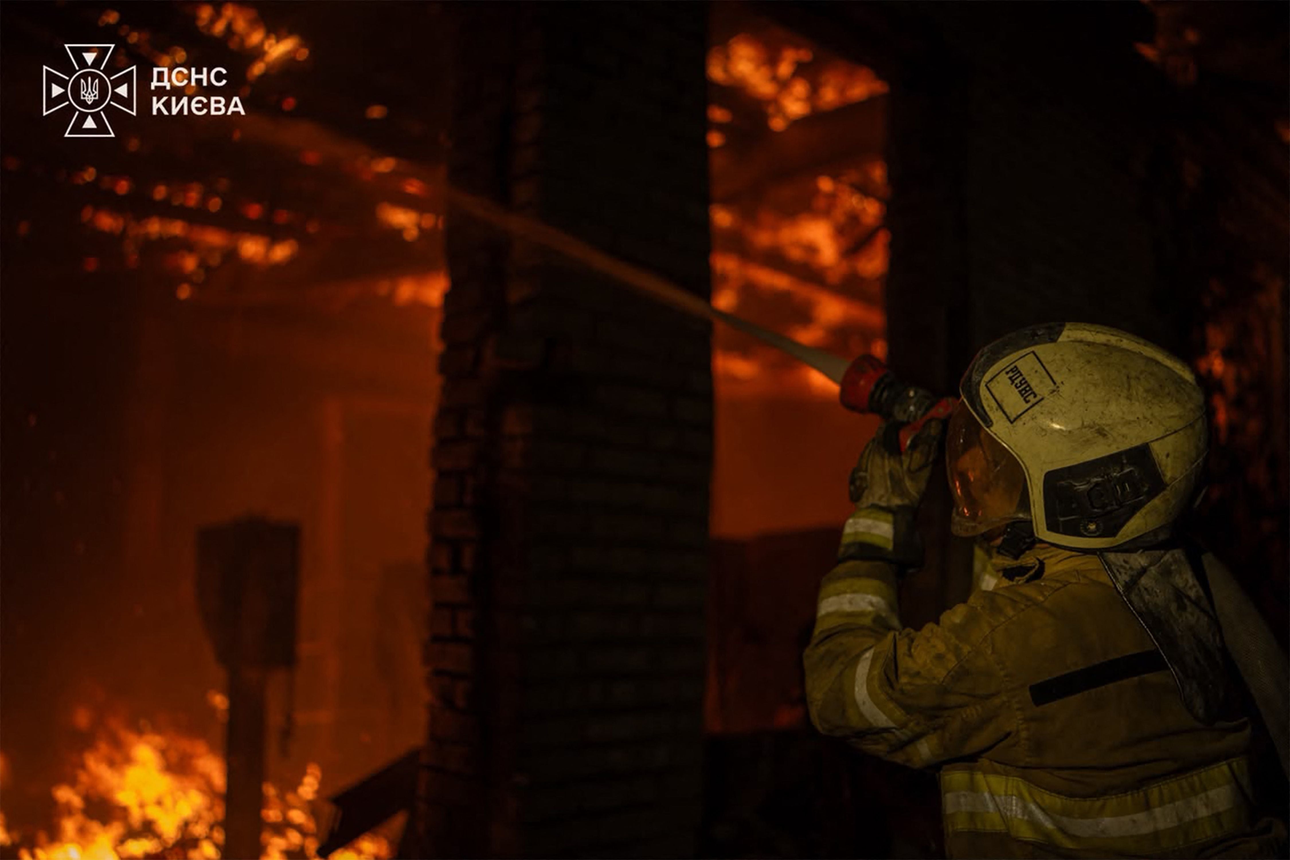 Ein Feuerwehrmann löscht einen Großbrand in einer Werkstatt bei Nacht in Kiew.