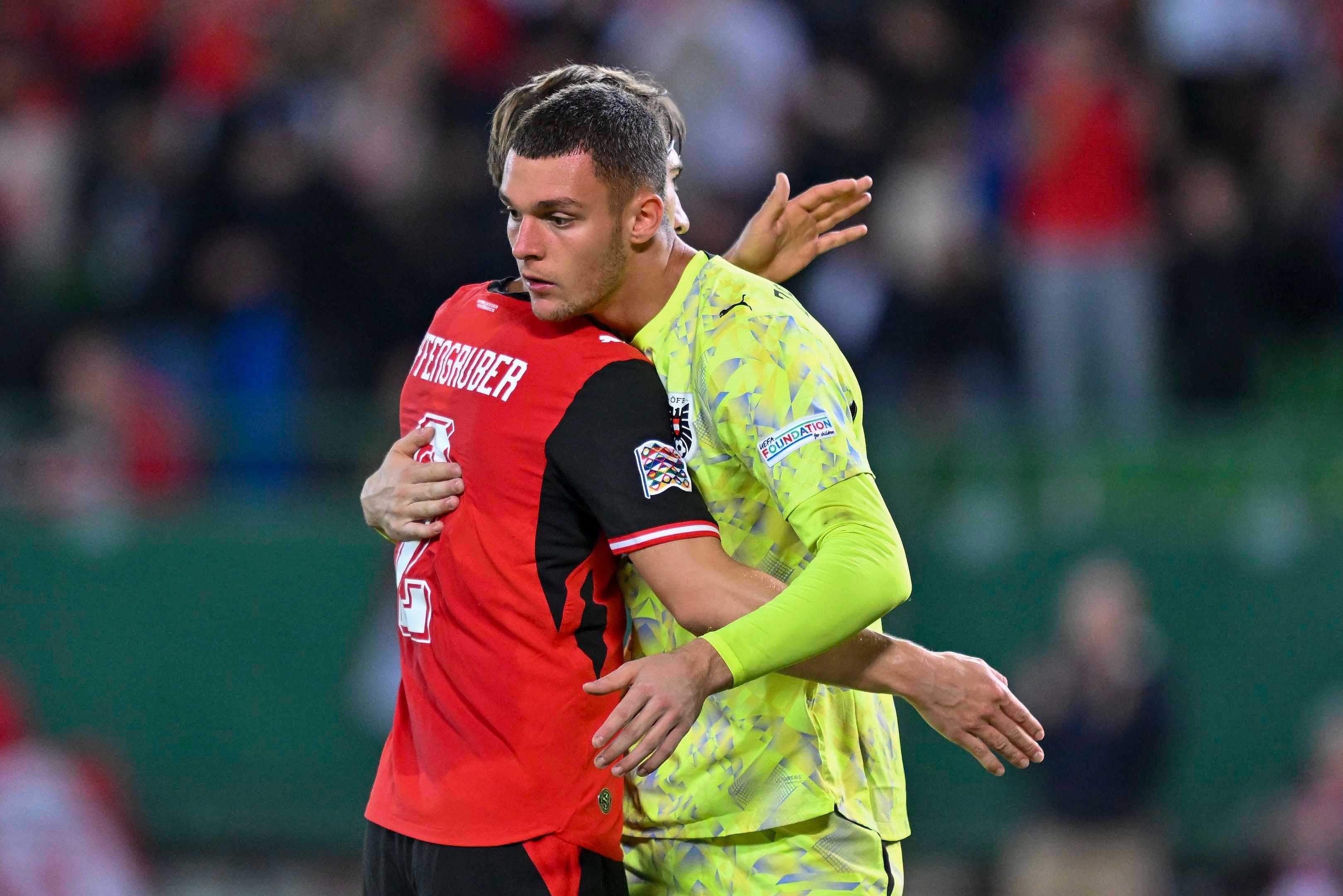 Zwei österreichische Fußballspieler umarmen sich nach einem Spiel auf dem Spielfeld.