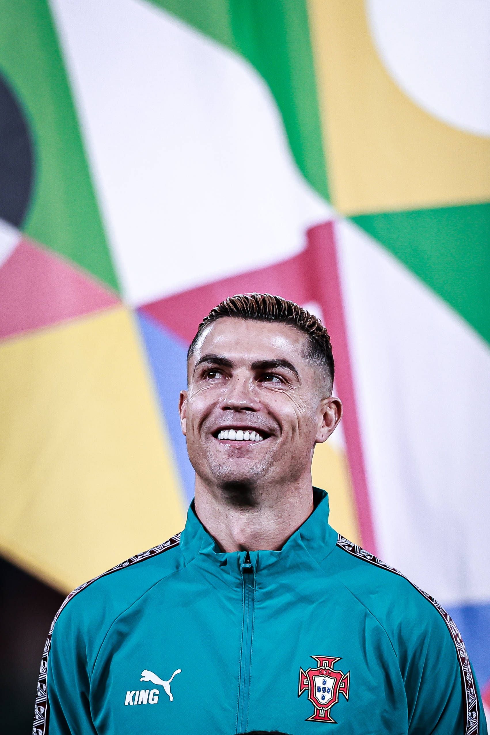 Cristiano Ronaldo lächelt in Nahaufnahme im dunkelgrünen Portugal-Trainingsanzug.