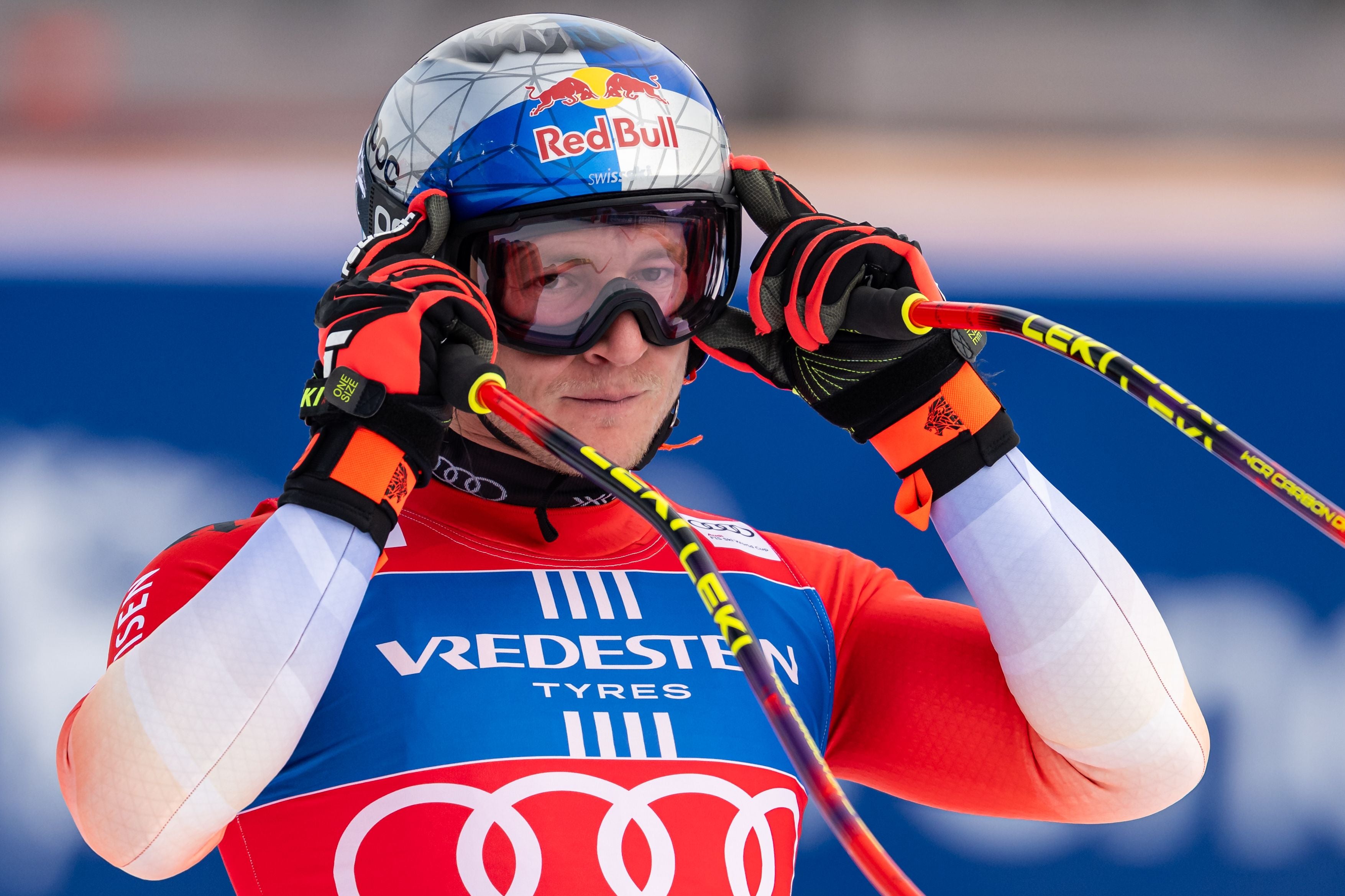 Ein Skirennfahrer mit Helm und Skibrille bereitet sich auf ein Rennen vor.