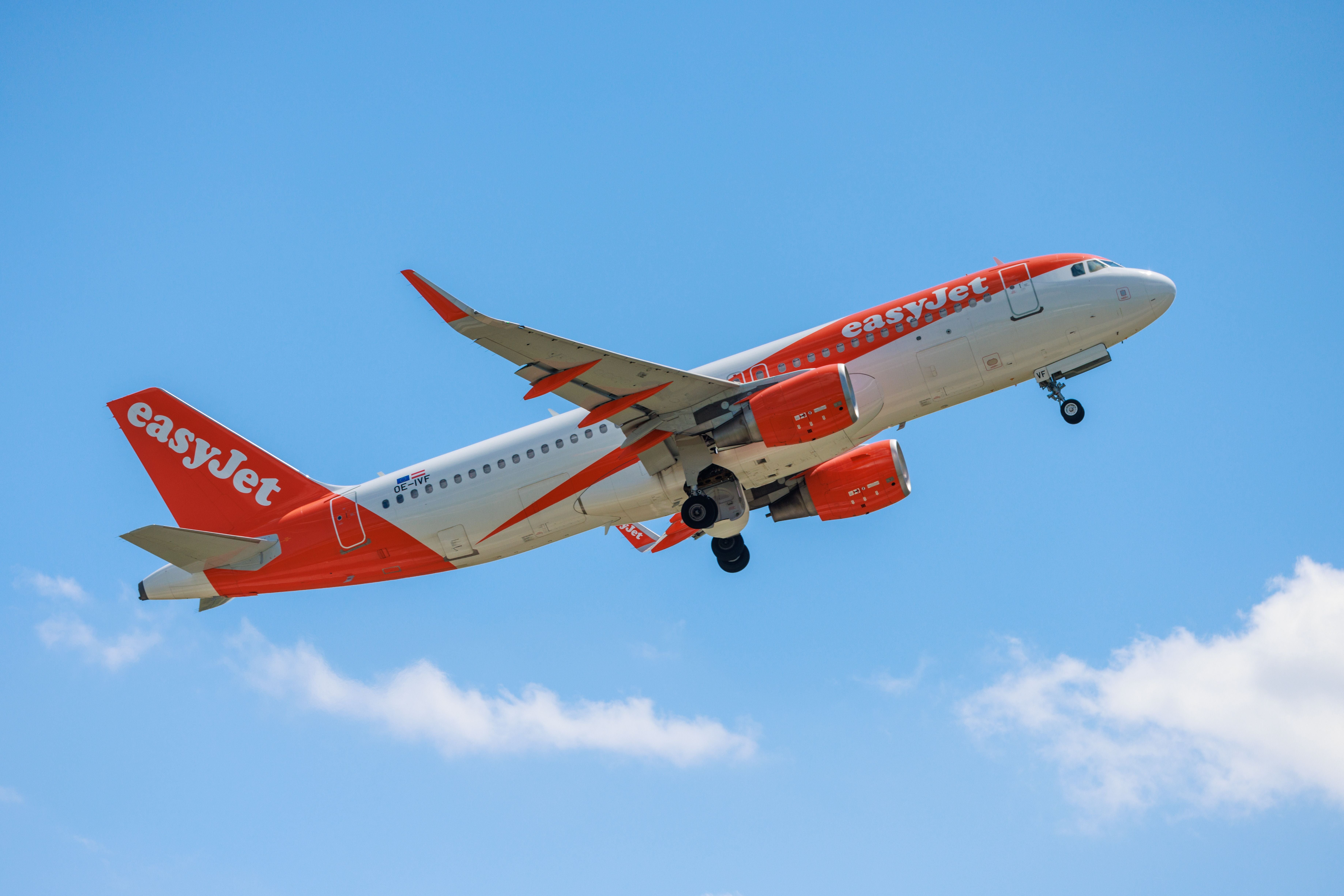 Ein EasyJet Airbus 319 fliegt bei blauem Himmel über Berlin.