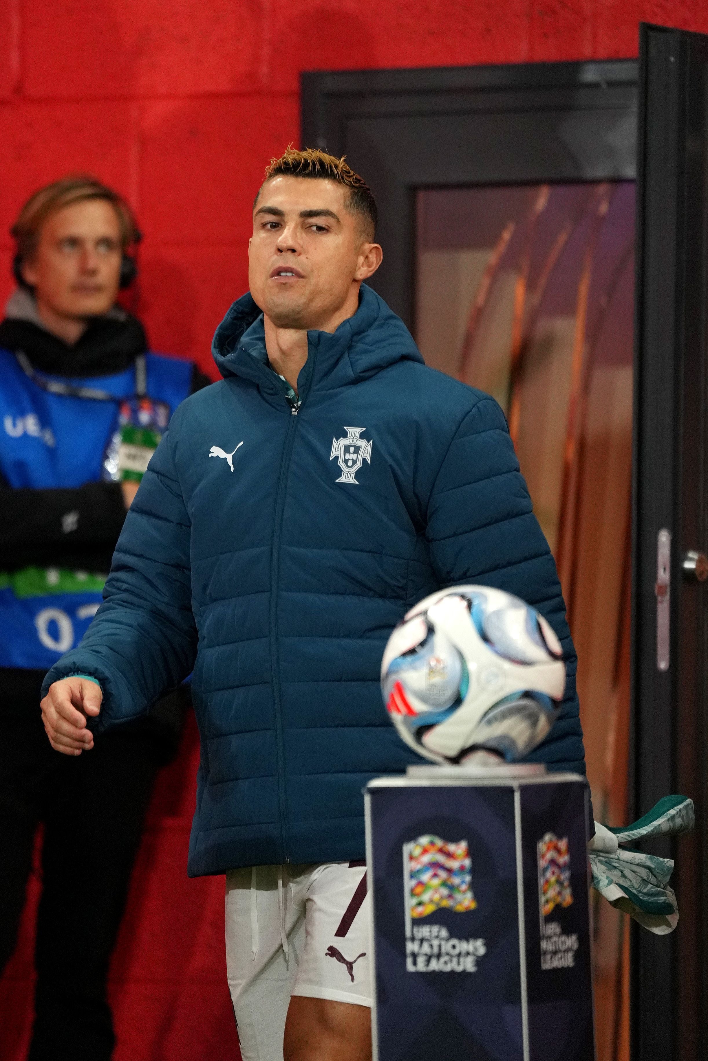 Ein portugiesischer Fußballspieler im Trainingsanzug steht neben einem UEFA Nations League Ball.
