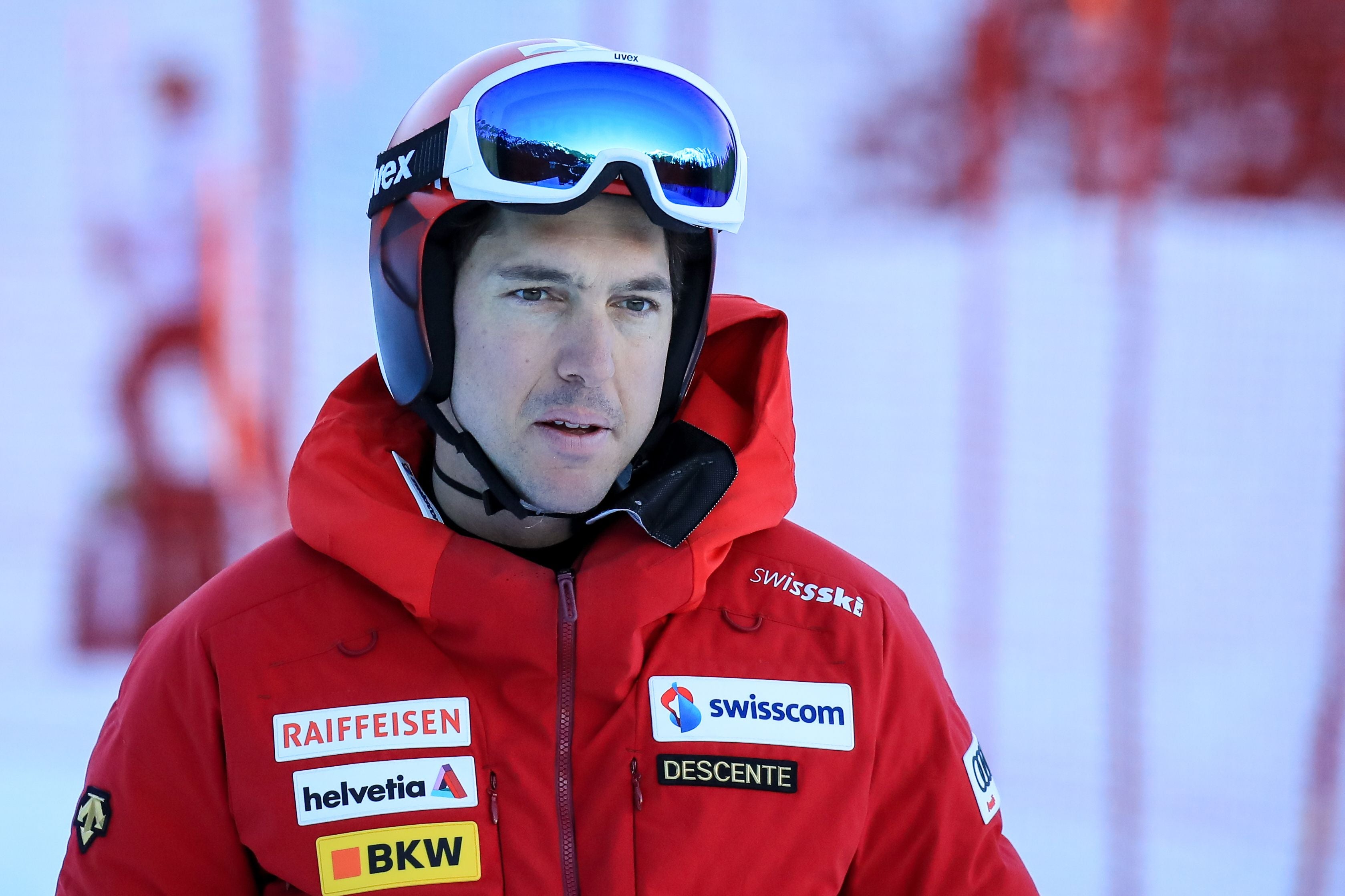 Ein Skifahrer im roten Teamanzug mit Helm und Skibrille bei der Streckenbesichtigung.