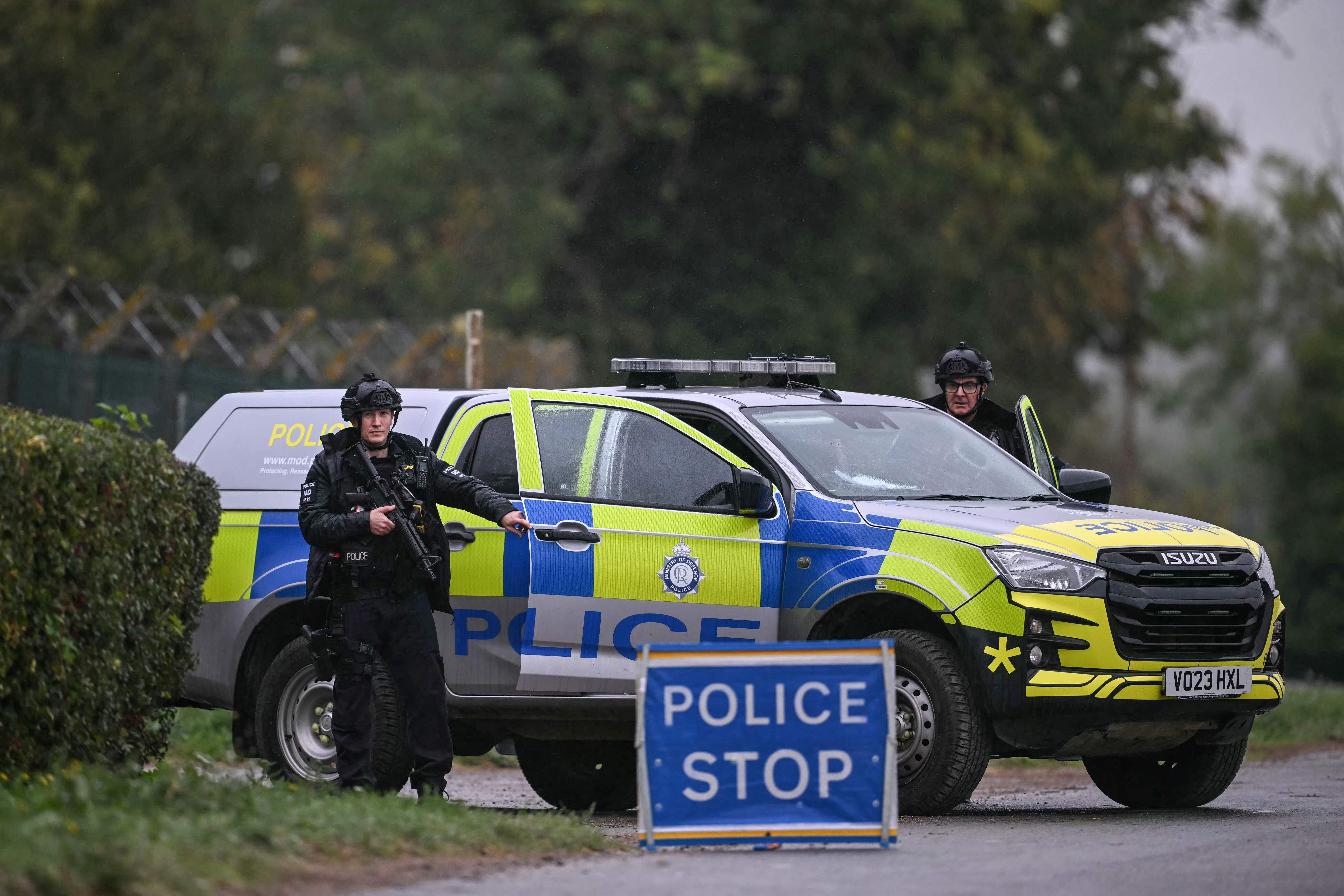 Bewaffnete Polizisten sichern eine Straßensperre vor einem britischen Polizeifahrzeug.