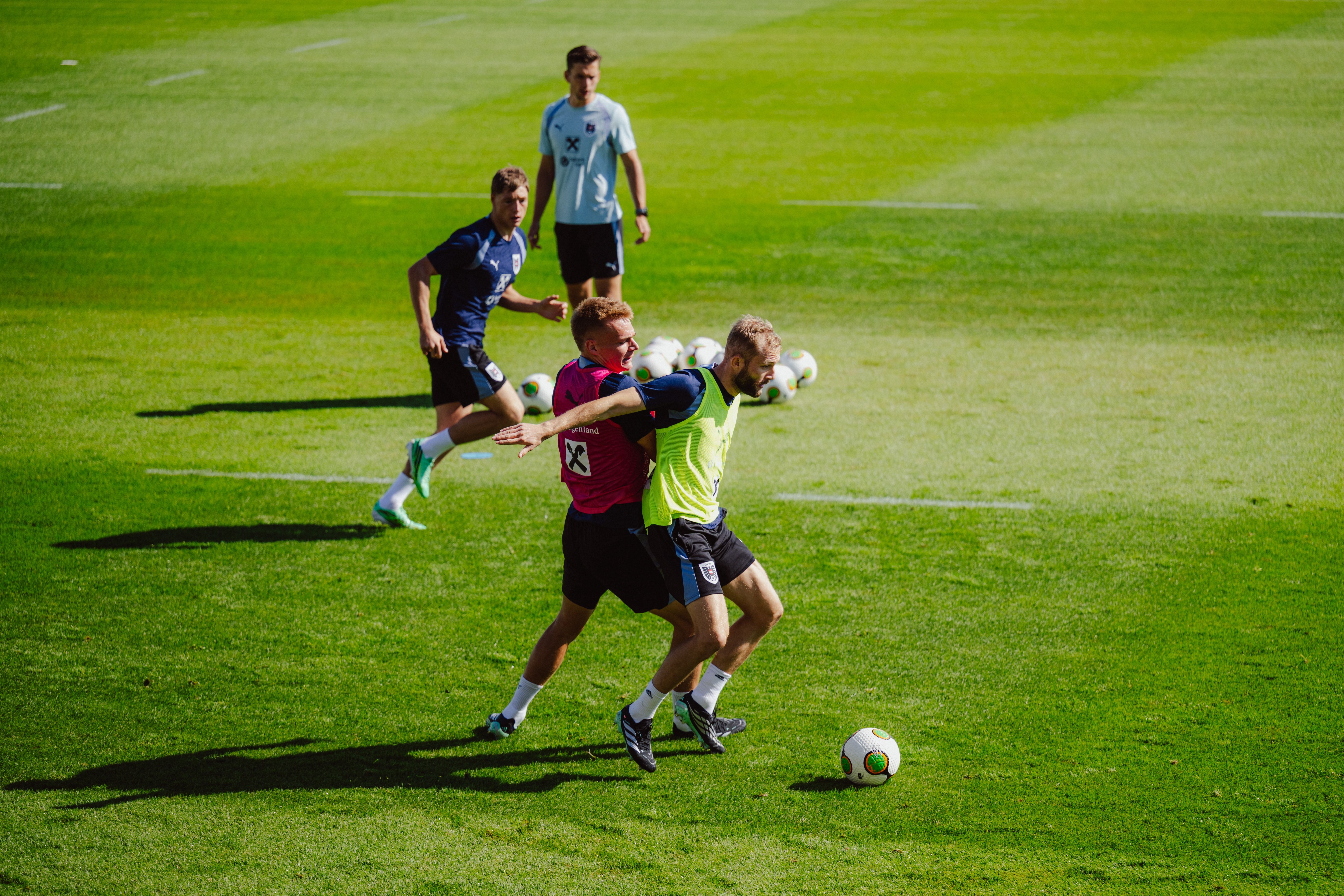Zwei Fußballspieler kämpfen im Training um den Ball, im Hintergrund weitere Spieler.
