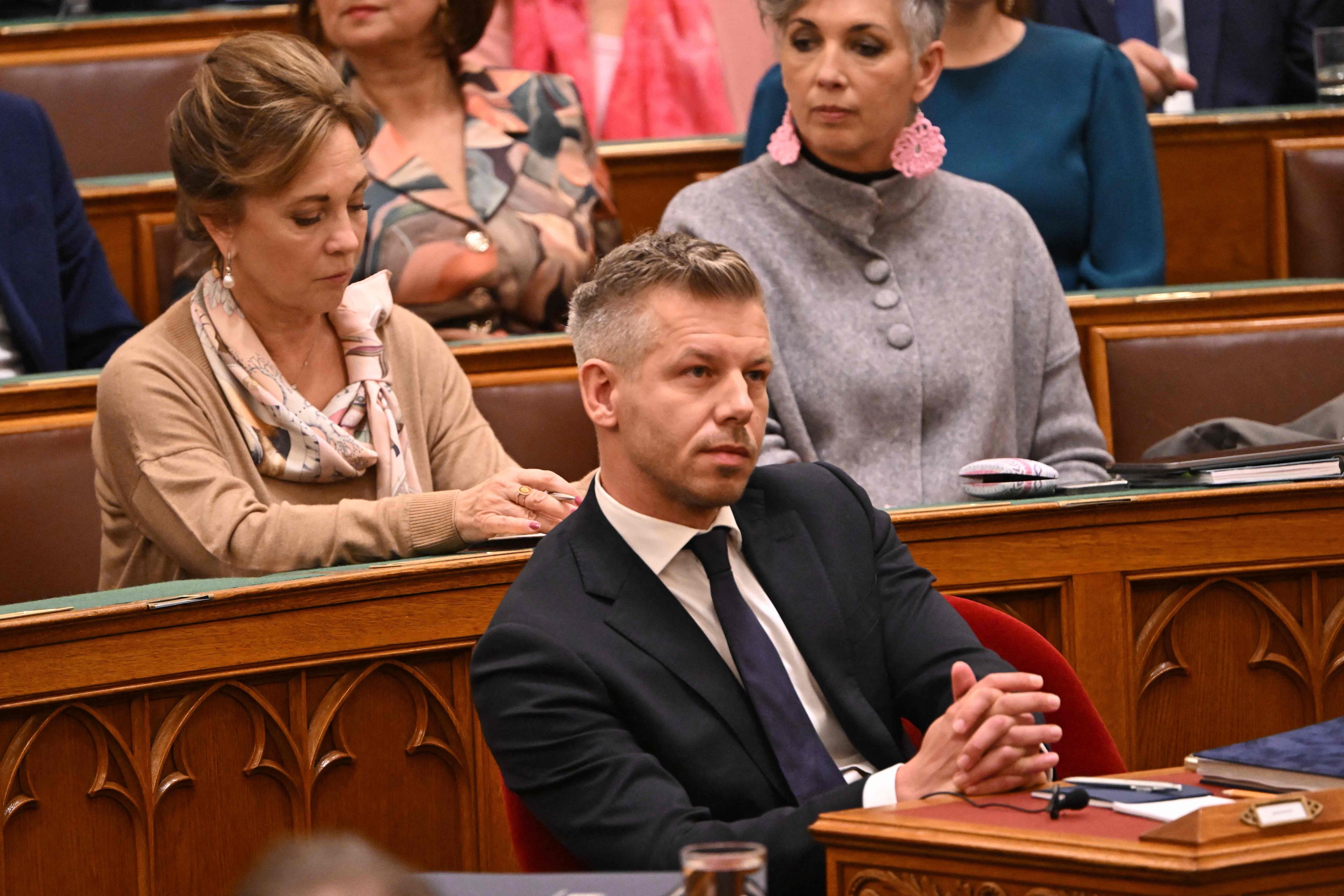 Peter Magyar sitzt in einem Anzug im ungarischen Parlament, Menschen sitzen hinter ihm.