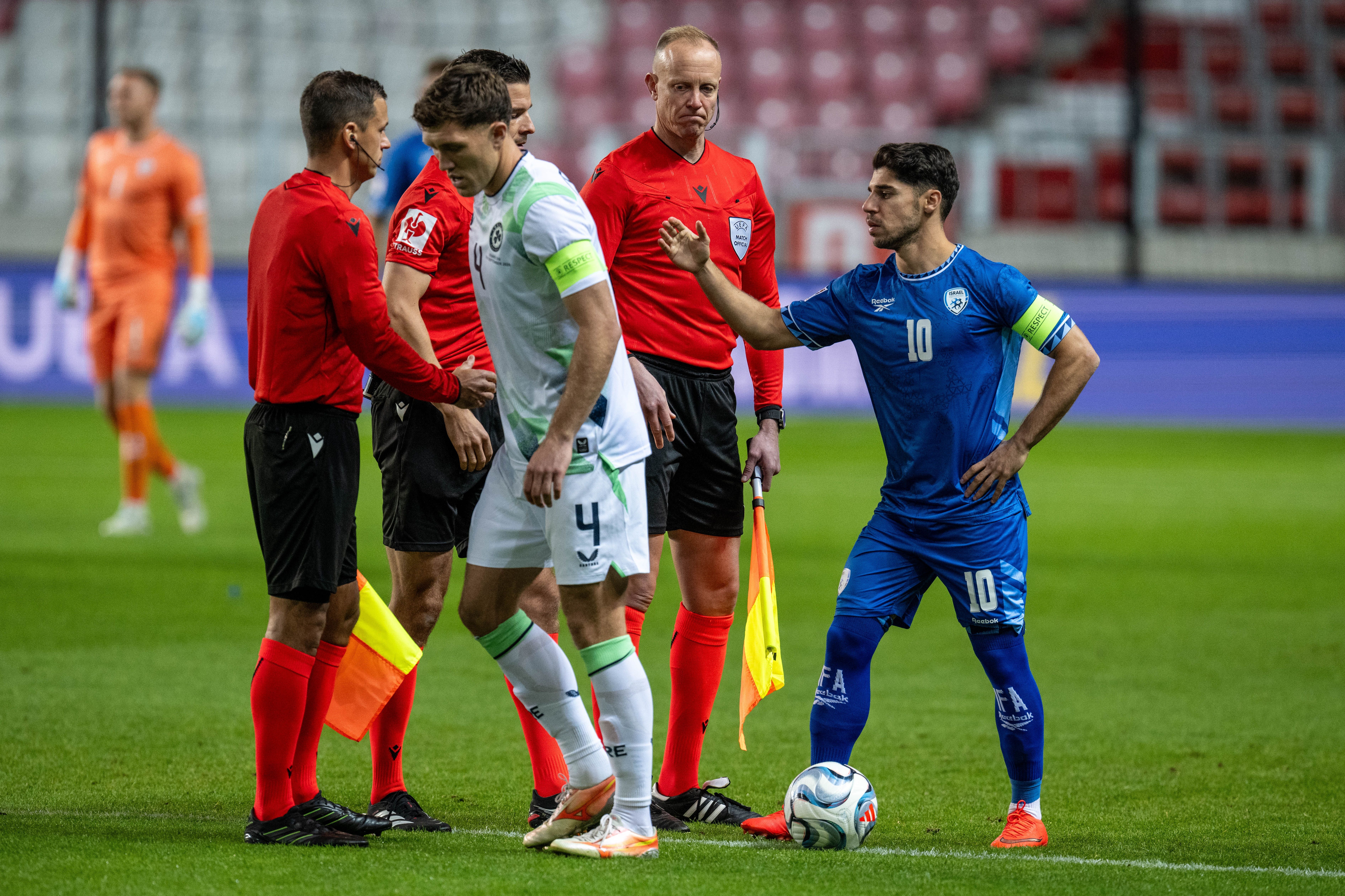 Zwei Fußballspieler diskutieren mit Schiedsrichtern während eines Spiels im Stadion.