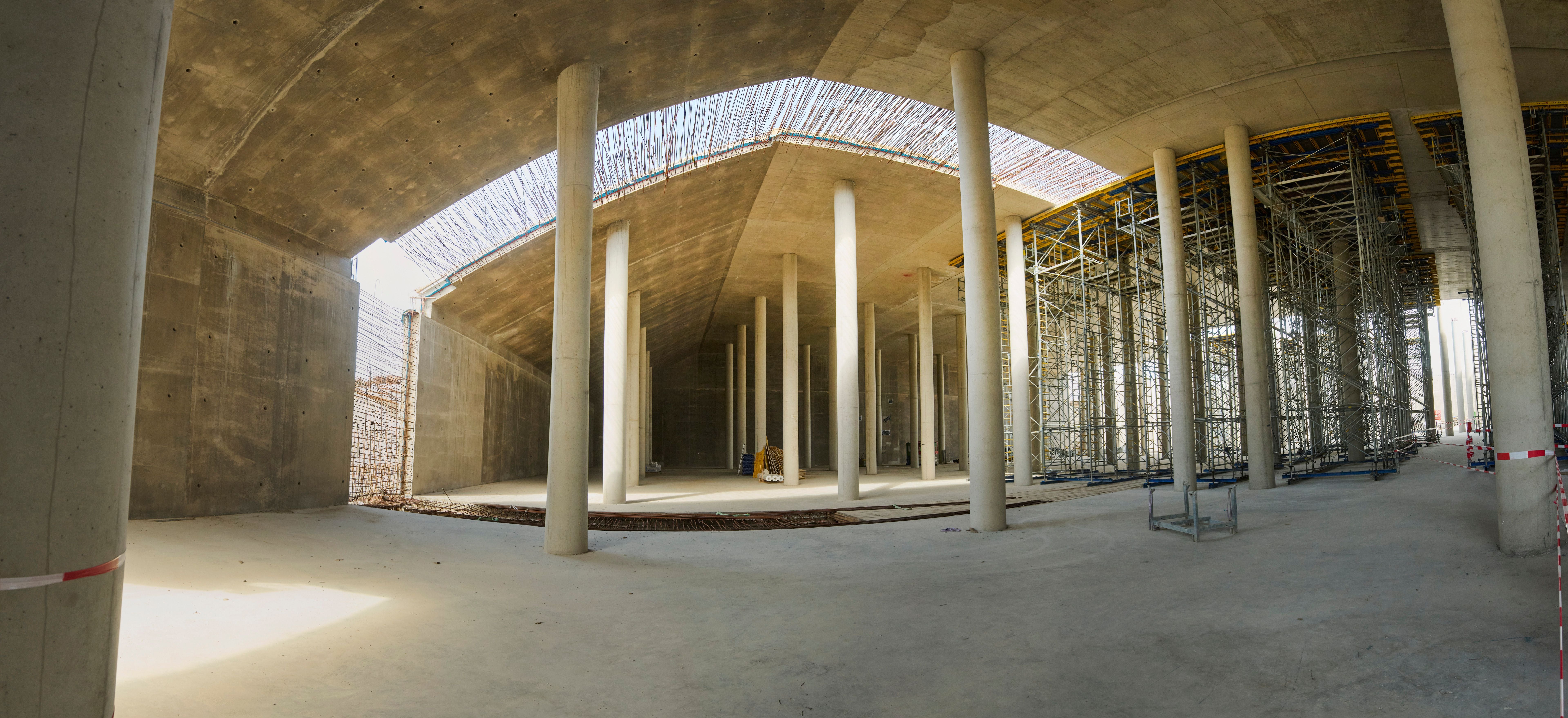 Großer Betonbau mit zahlreichen Säulen und Baugerüsten auf einer Baustelle.