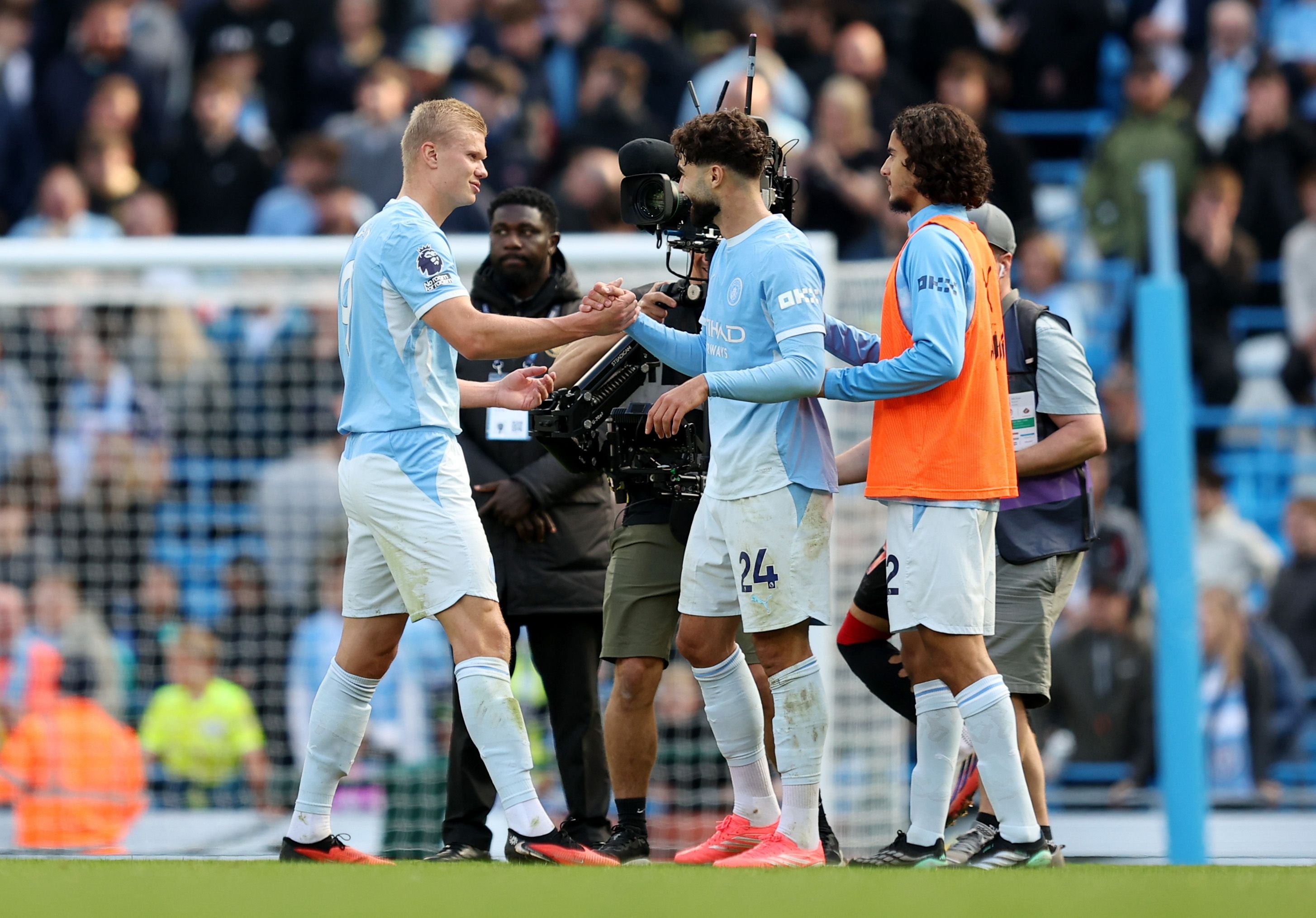Drei Manchester-City-Spieler feiern nach einem Fußballspiel auf dem Spielfeld.