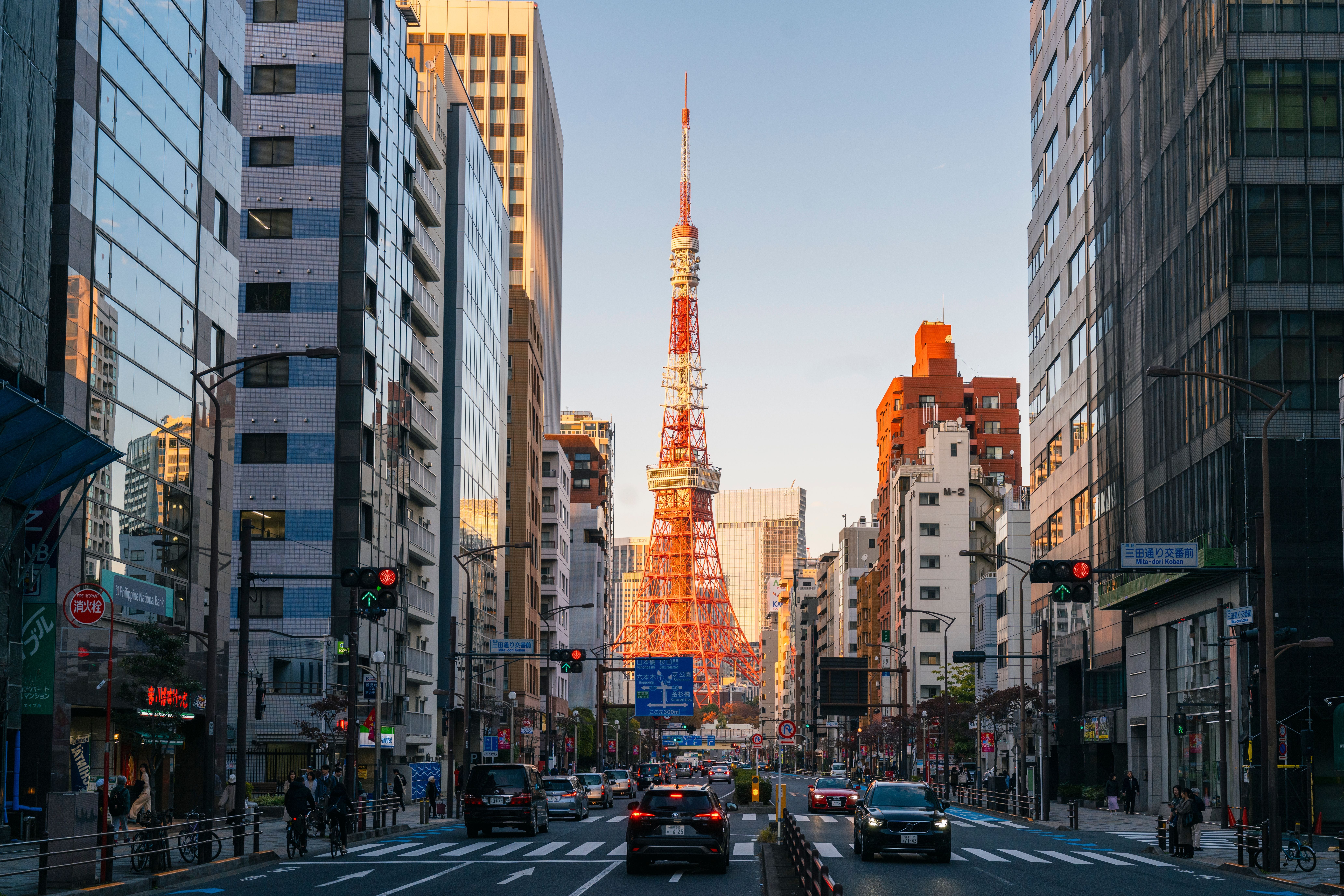 Straßenszene in Tokio mit dem Tokyo Tower im Hintergrund, umgeben von modernen Gebäuden.