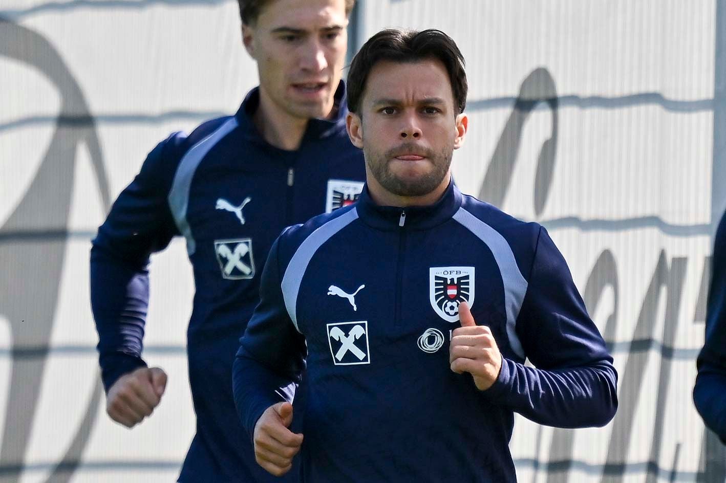 Zwei Fußballspieler im Trainingsanzug des österreichischen Nationalteams beim Laufen.